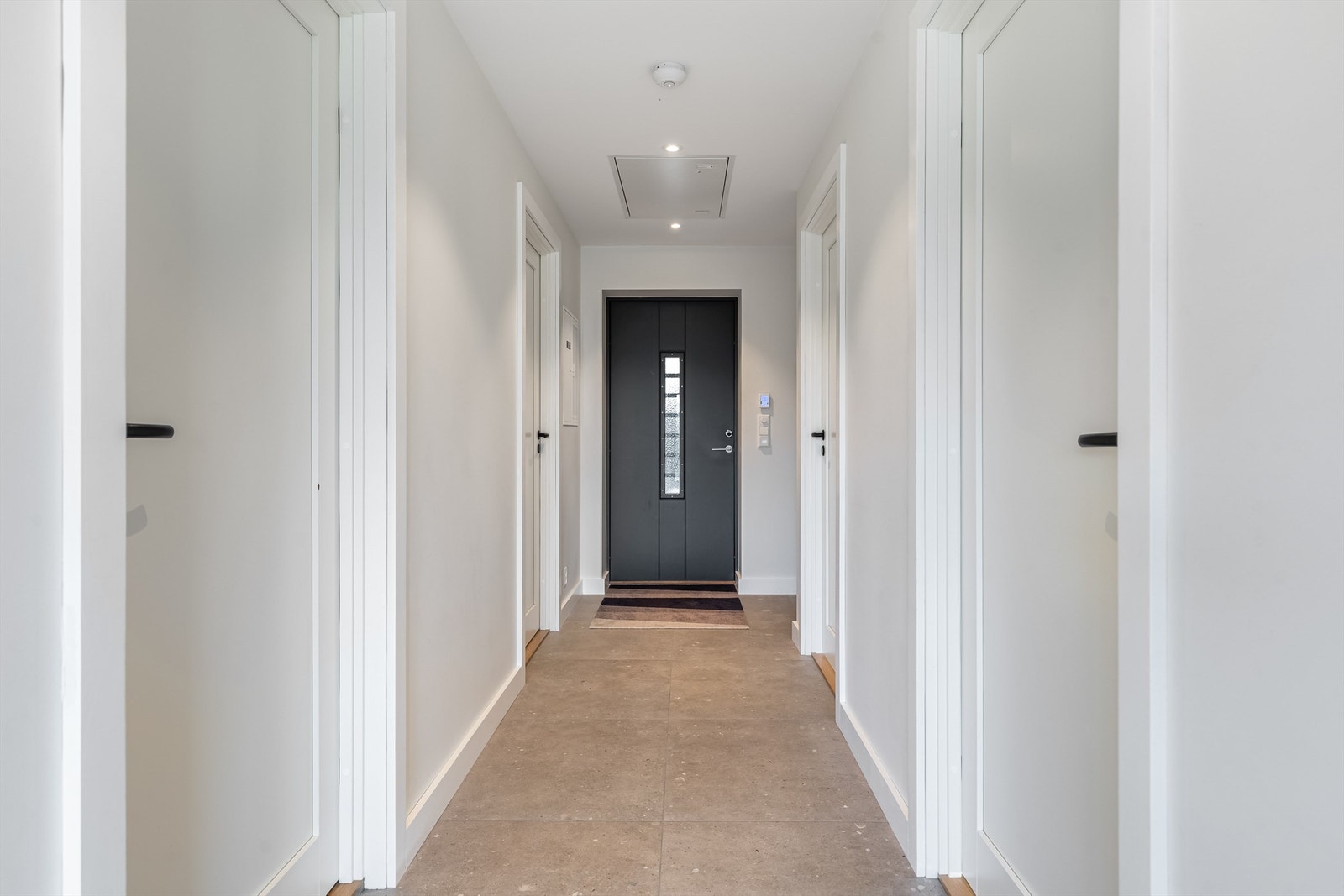 Lengre gang med flis og sorte dørhåndtak. Galleribilde