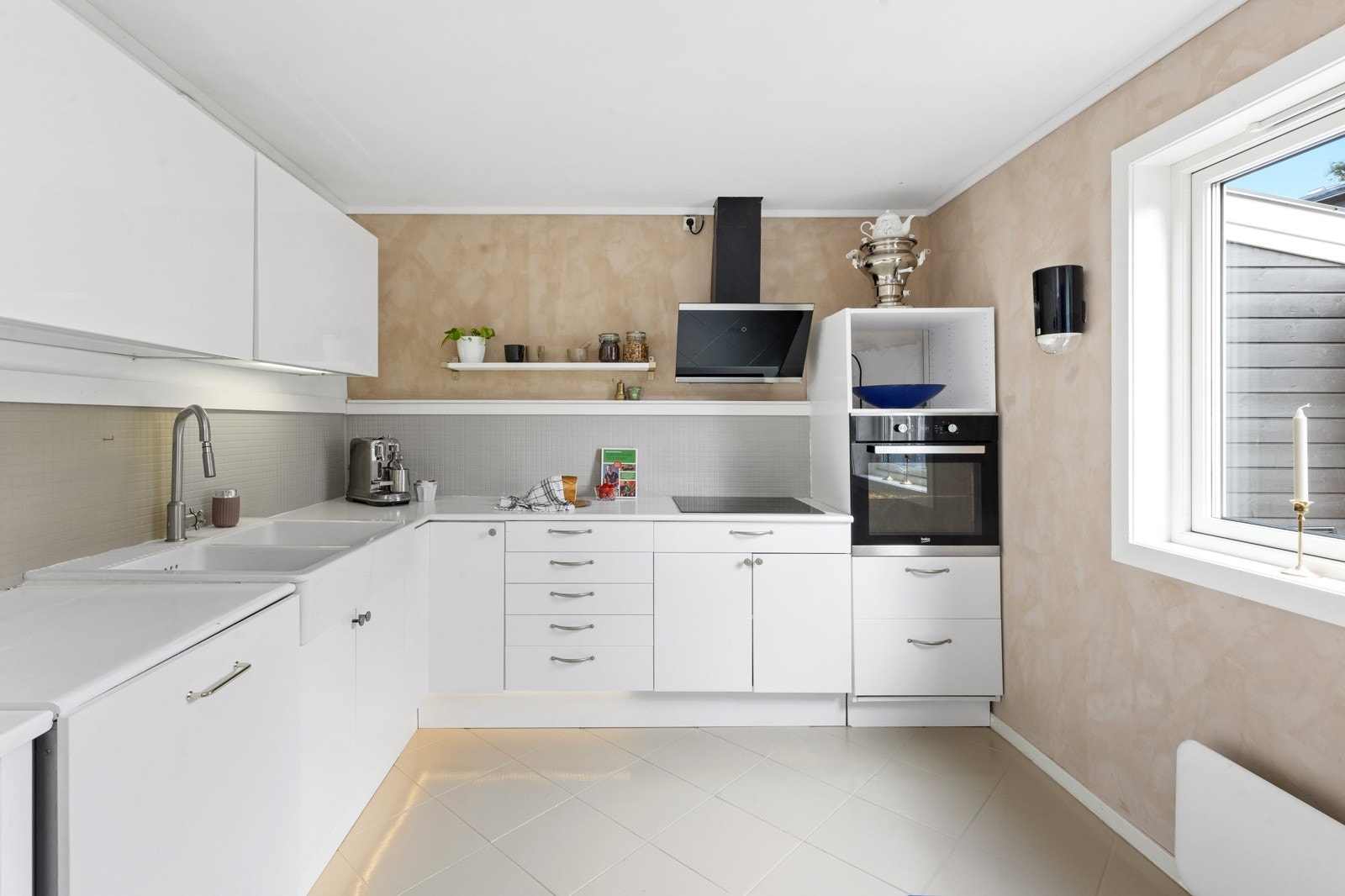 Kjøkkenet er utstyrt med slette fronter og malt heltre benkeplate og oppleves luftig med store vindufslater Galleribilde