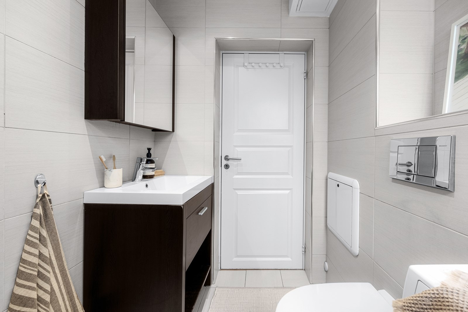 Rommet er utstyrt med servantinnredning, speilskap, veggmontert toalett, dusjhjørne med glassdører og opplegg for vaskemaskin. Galleribilde