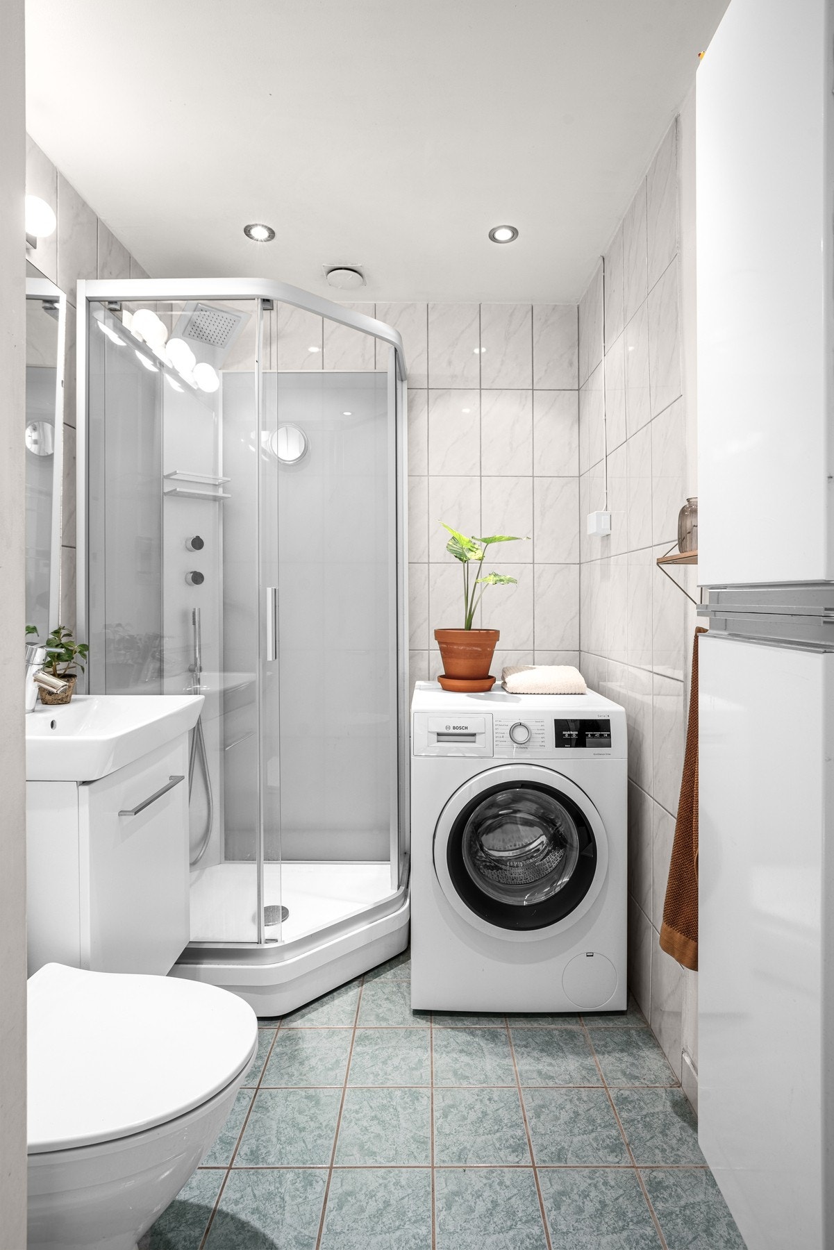Flislagt bad med downlights i tak og opplegg for vaskemaskin Galleribilde