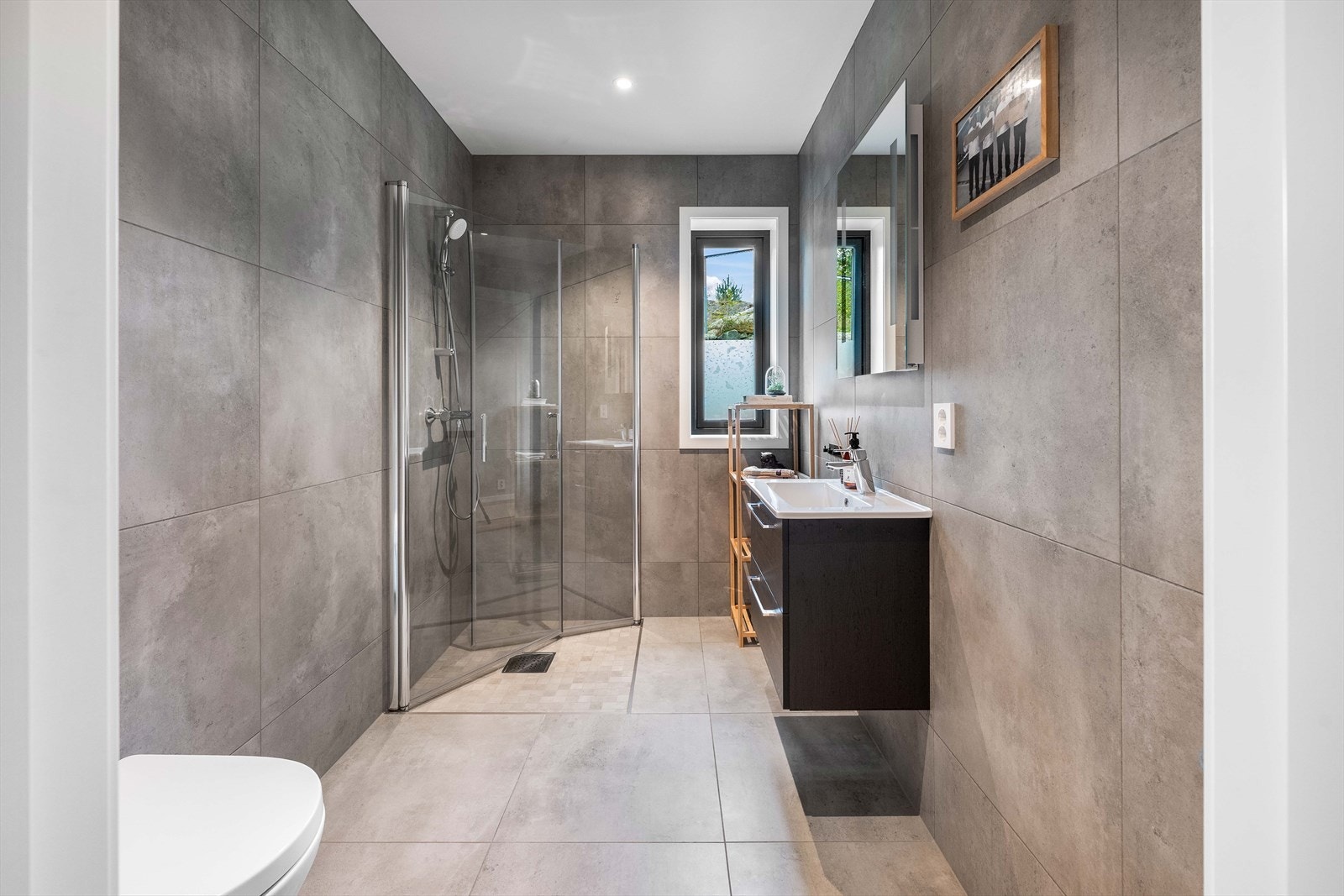 Flislagt bad med dusjhjørne og moderne innredning - komfortabelt og lett tilgjengelig. Galleribilde