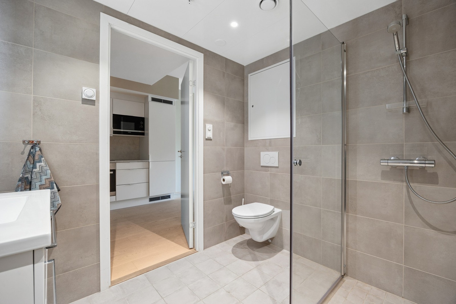 Badet er utstyrt med vegghengt servantinnredning, speil med belysning, dusjhjørne, vegghengt toalett og opplegg for vaskemaskin. Galleribilde