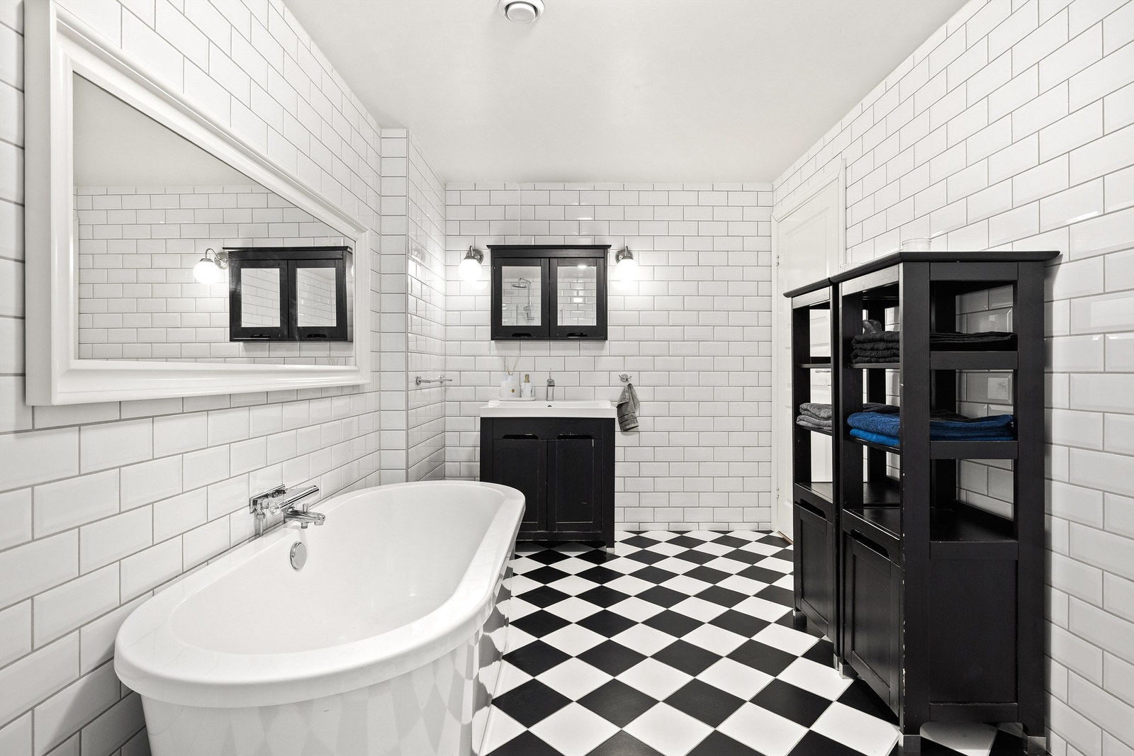 Rommet har flislagt gulv med behagelig gulvvarme og helflisede vegger i hvit fasettflis. Svarte kontraster på innredning og gulv skaper et elegant og tidløst uttrykk. Galleribilde