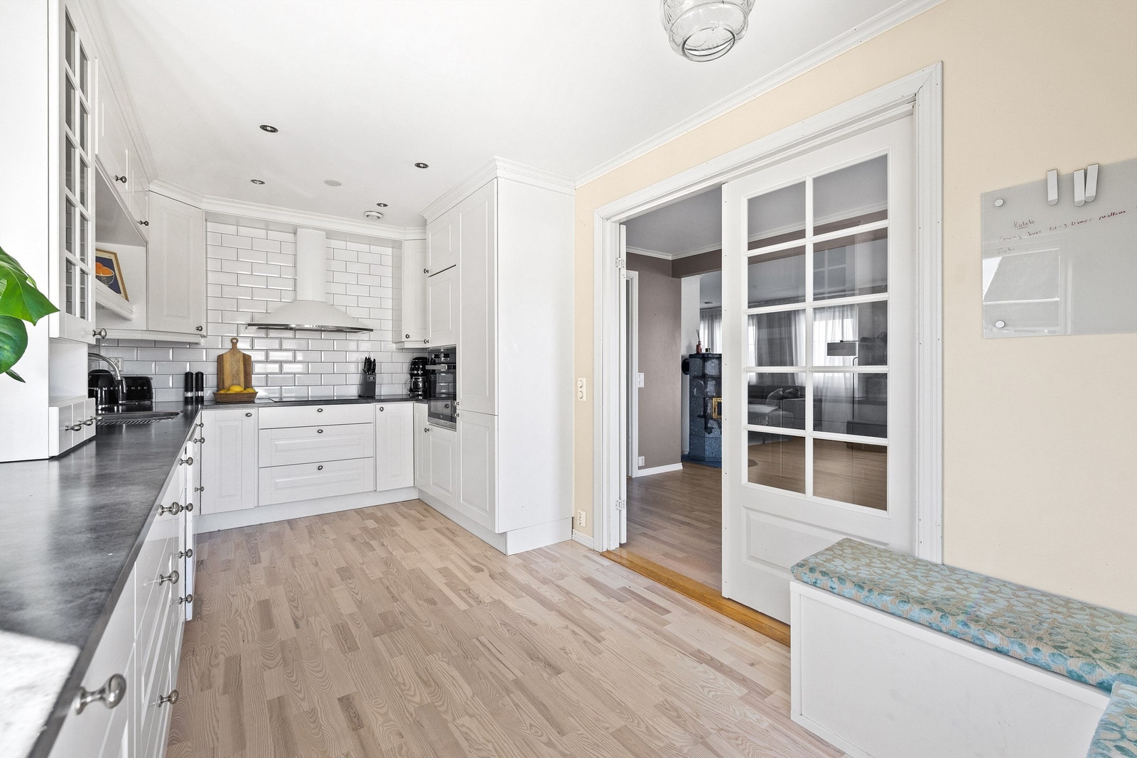 Kjøkkenet har en tidløs og gjennomført stil med profilerte fronter, hvite fliser over benk og integrerte hvitevarer. Galleribilde