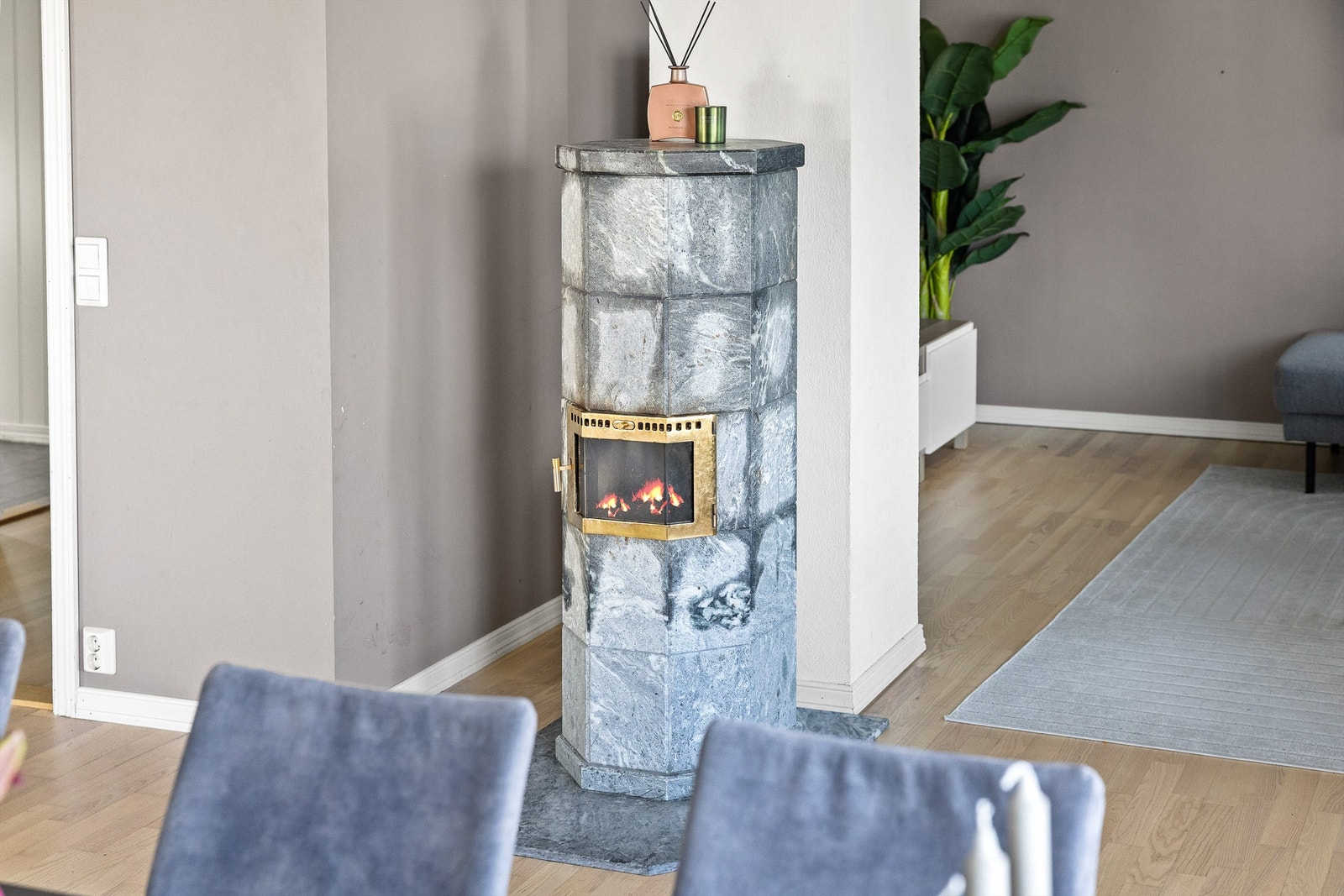 Midt i rommet står en stilren klebersteinsovn - både funksjonell og dekorativ, og perfekt til boligens helhetlige stil. Galleribilde