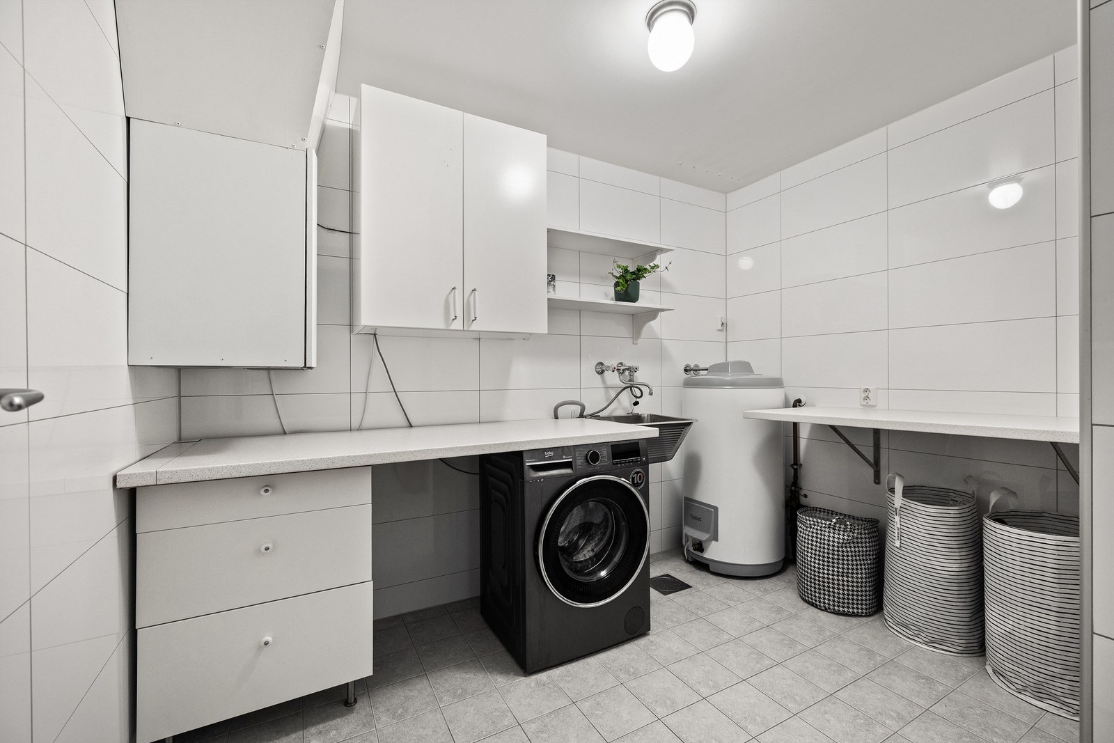 Vaskerommet har flislagte vegger og flislagt gulv med behagelig gulvvarme. Rommet er innredet med skap og benkeplater som gir rikelig med oppbevarings- og arbeidsplass. Det er praktisk utslagsvask og opplegg for vaskemaskin Galleribilde