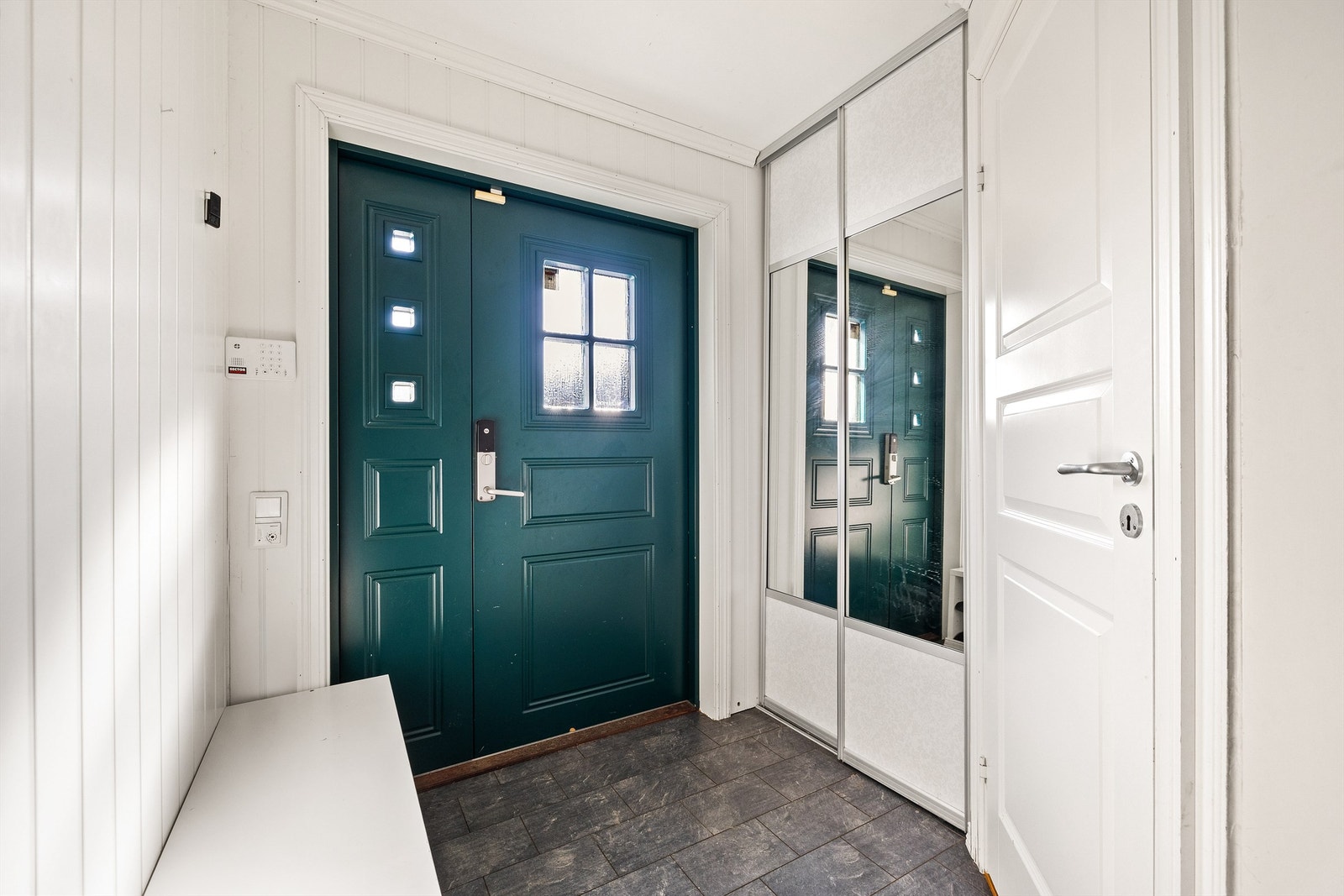 Velkommen inn! Entréen har lyse overflater og en praktisk skyvedørsgarderobe med speilfronter som gir både god lagringsplass og et luftig inntrykk. Galleribilde