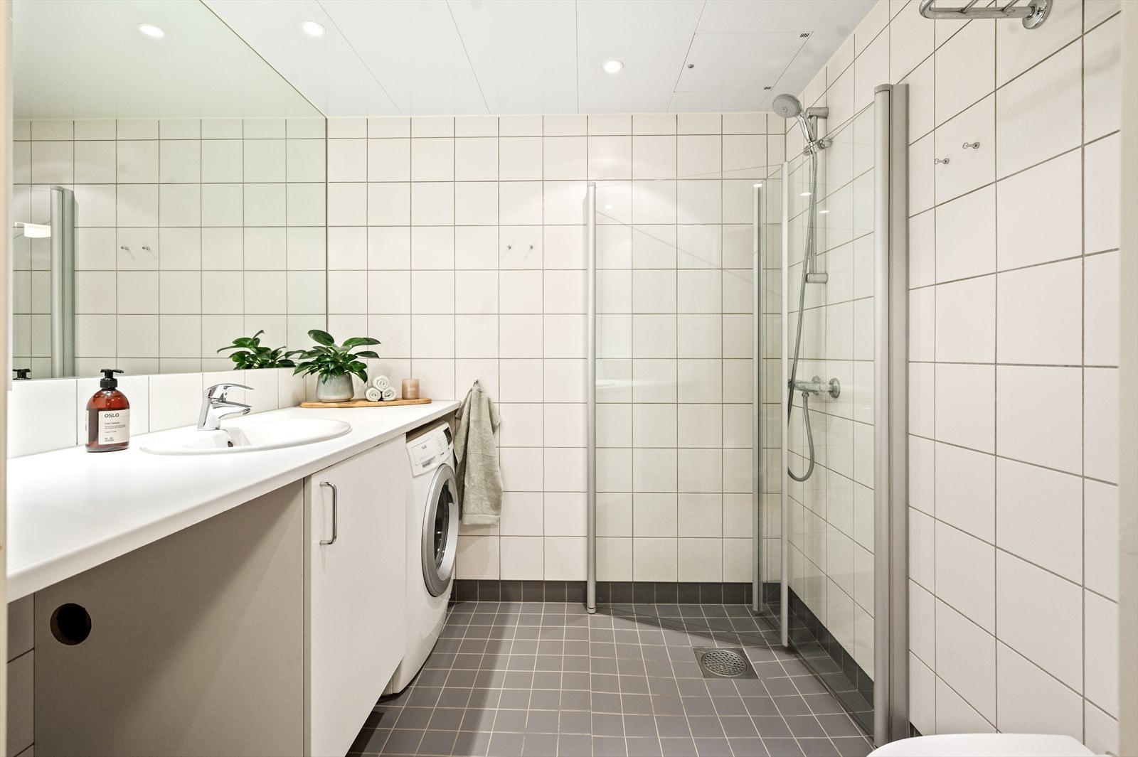 Badet er romslig med hvite fliser på vegger og lysegrå på gulv med gulvvarme under Galleribilde