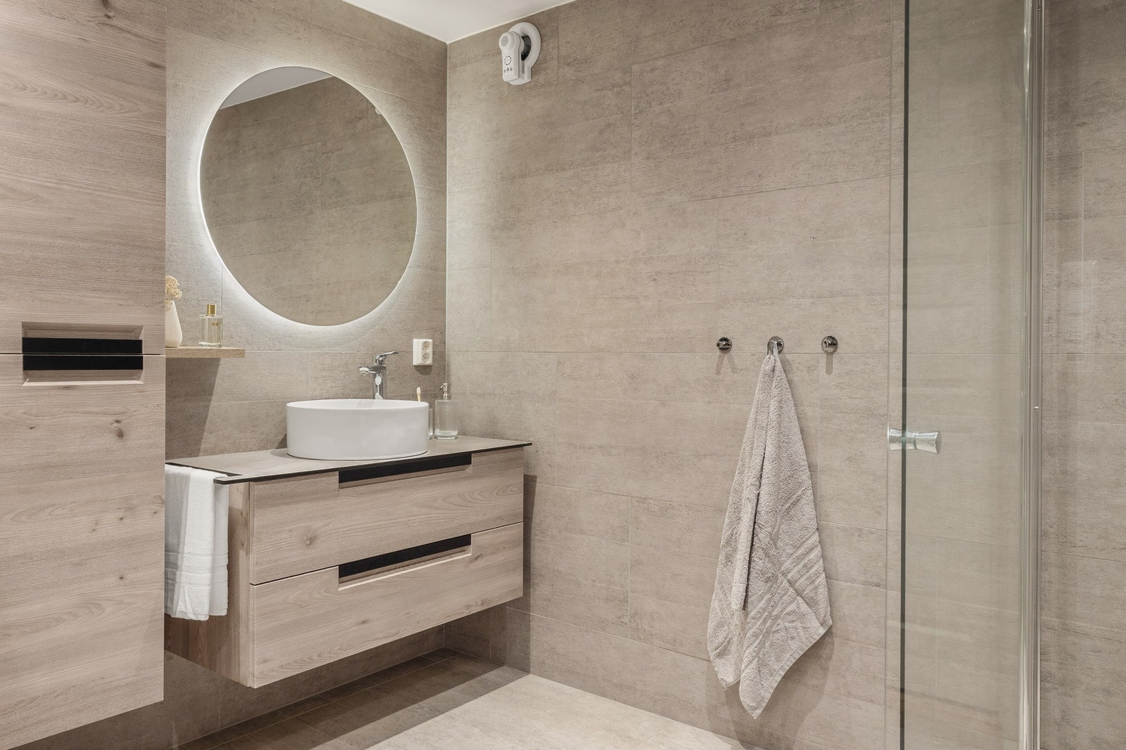 Badet er innredet med vegghengt toalett, baderomsinnredning og dusj med glassvegger. Galleribilde