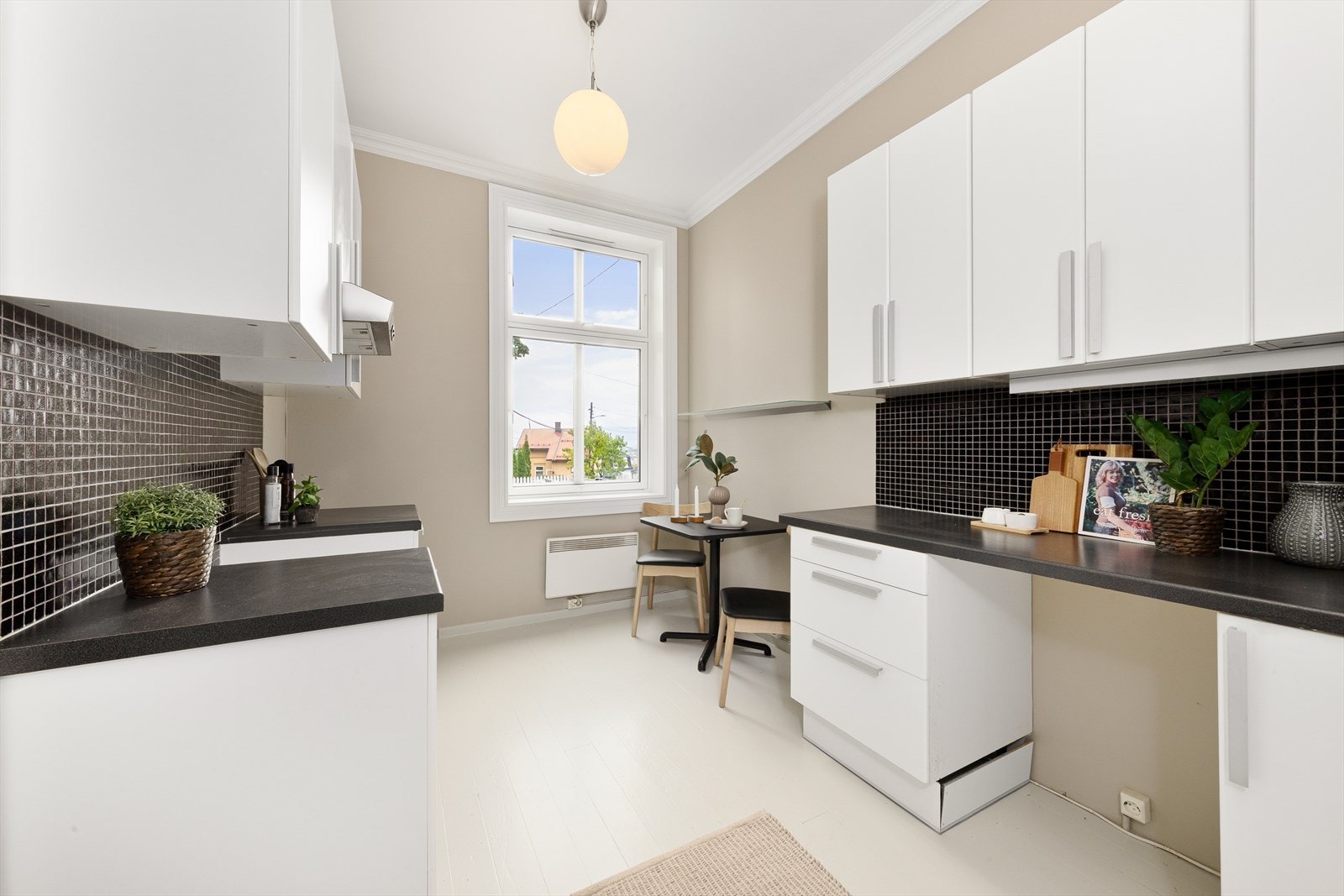 Kjøkkenet har innredning med glatte fronter og benkeplate av laminat og fliser mellom over- og underskap. Galleribilde