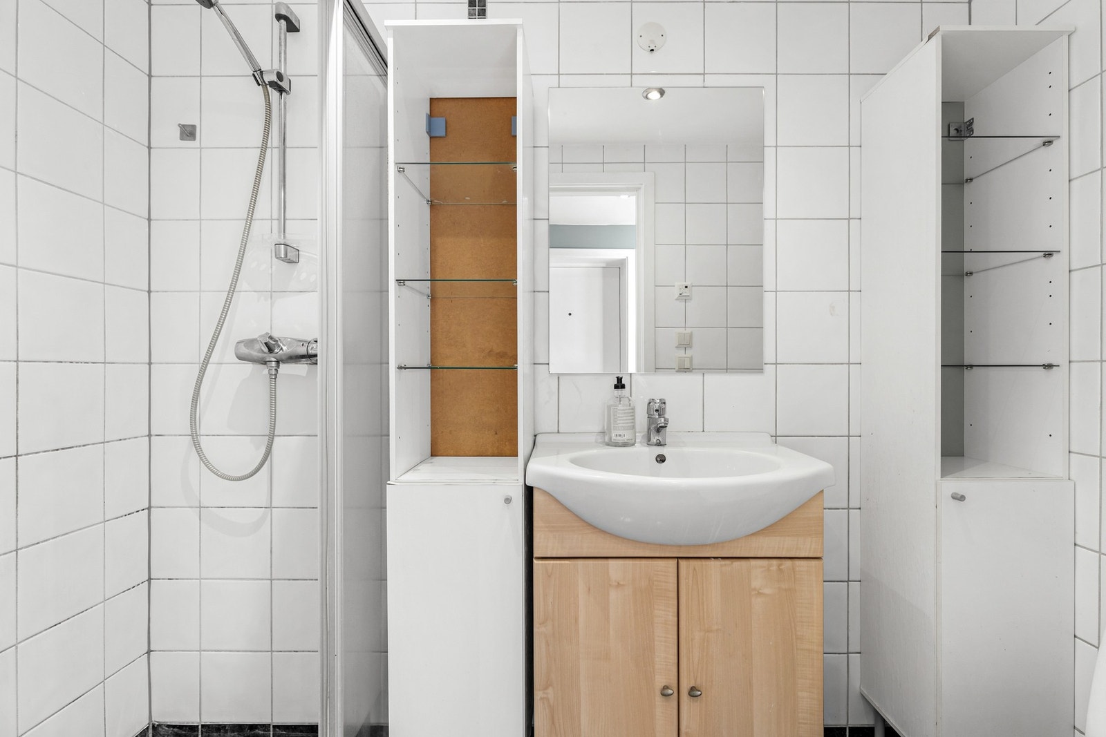 Pent baderom med fliser og varme i gulv. Videre inneholder badet servant i innredning, speil, høyskap og dusjhjørne. Galleribilde