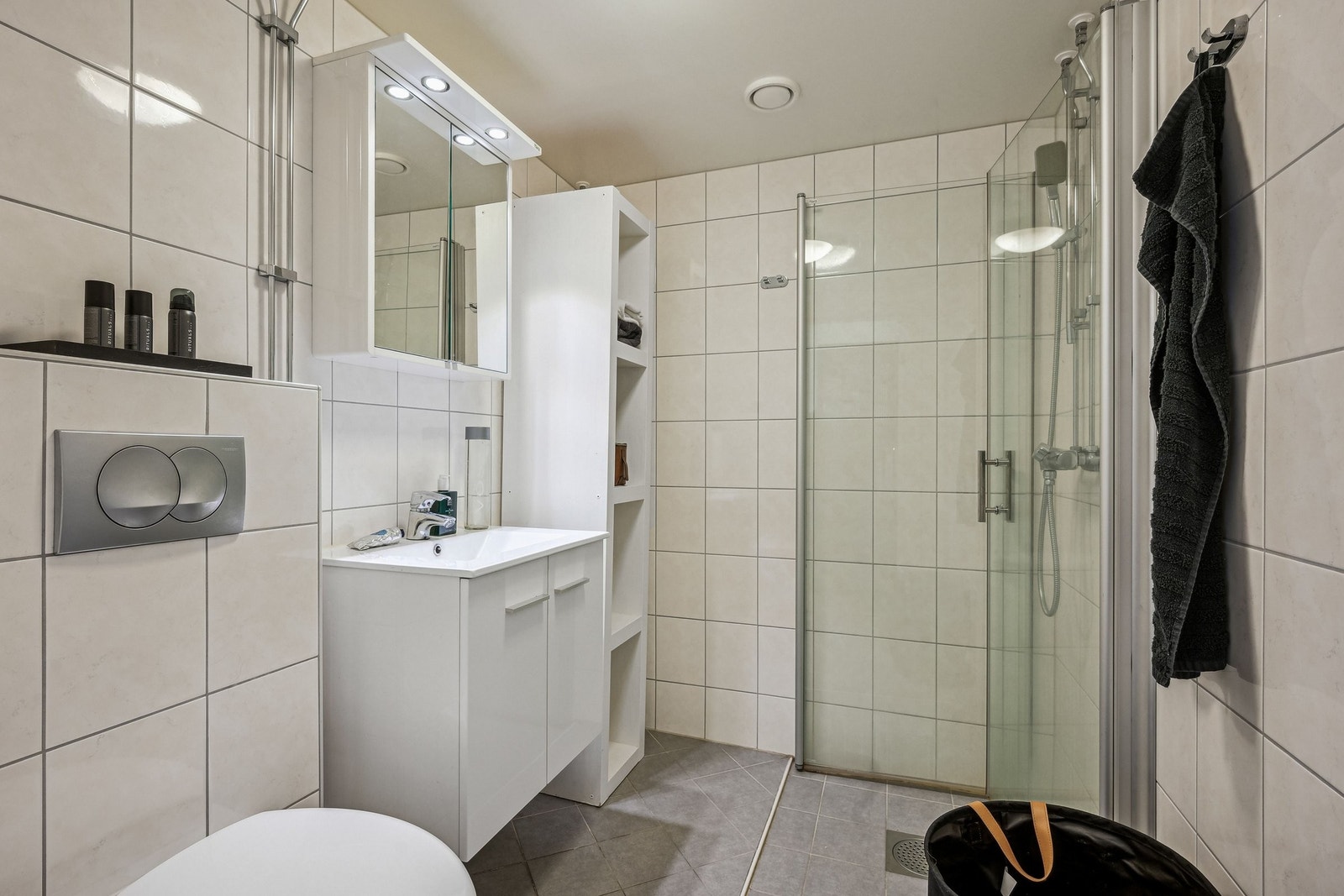 Lyst og funksjonelt bad fra 2014 med nedfelt servant, skap, veggmontert toalett, dusjhjørne og opplegg for vaskemaskin. Flislagte overflater og gulvvarme gir ekstra komfort. Galleribilde