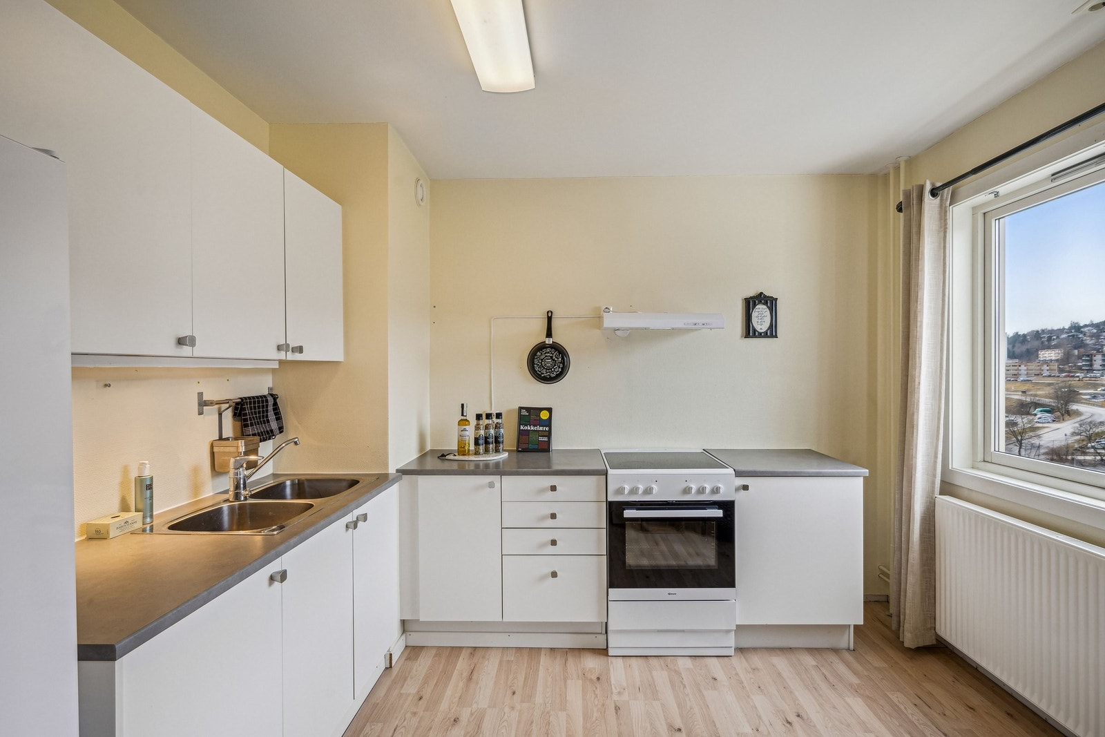 Stilrent kjøkken med hvite fronter, oppvask- og skyllekum. God skapplass og benkeplate gjør det ideelt for matlaging. Avtrekksvifte sikrer ekstra komfort. Galleribilde