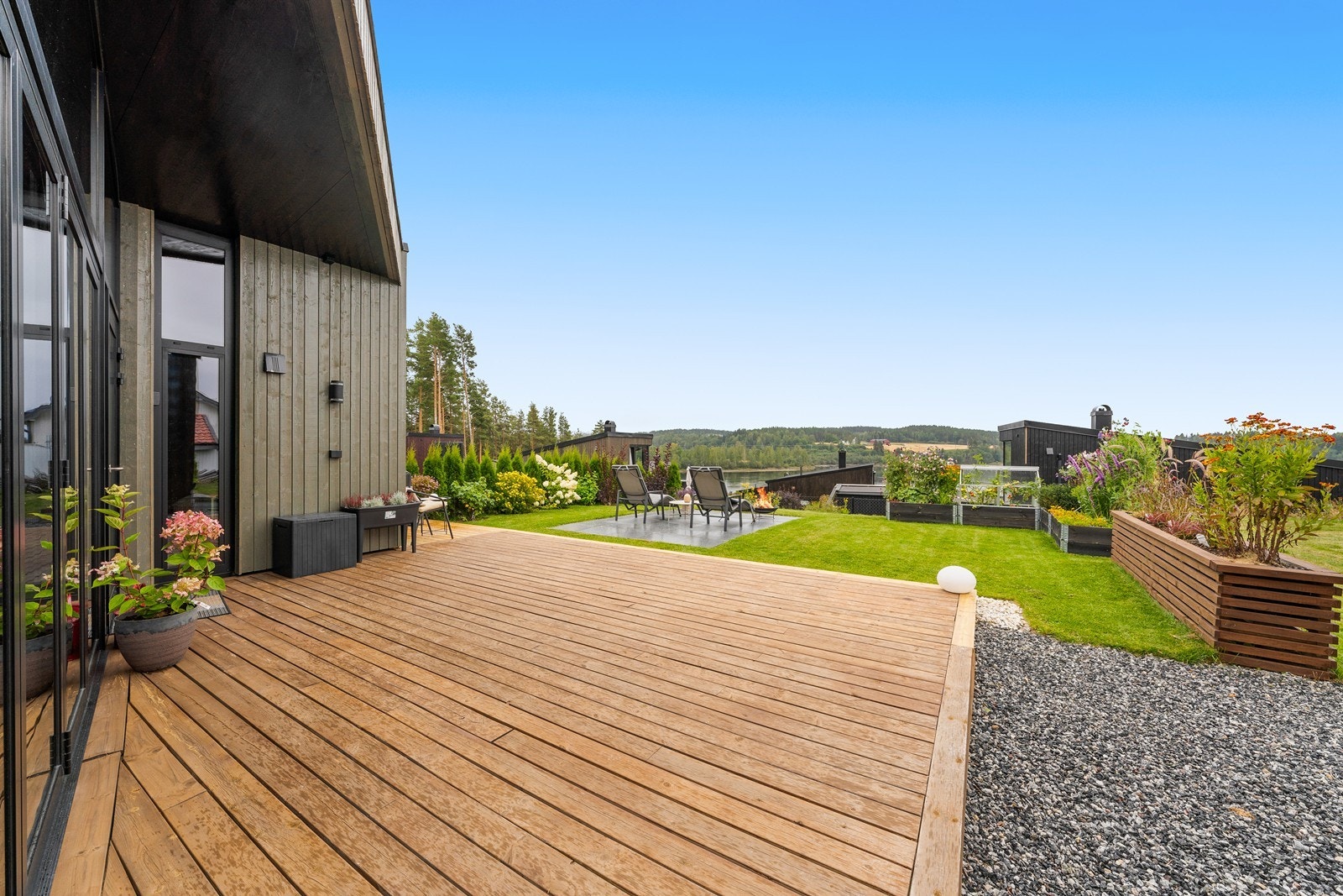 Stor terrasse med god plass til utemøbler og utsikt mot hagen og videre mot vannet. Galleribilde