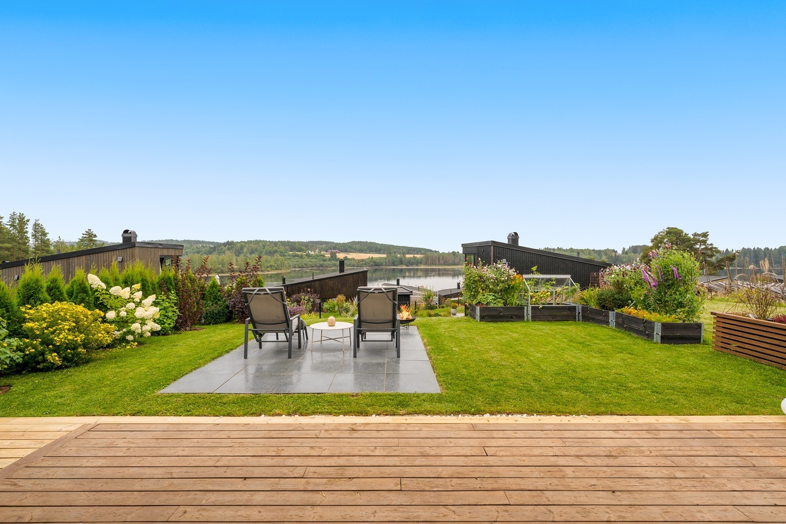 Romslig terrasse med utsikt mot åpent landskap og frodig hage. Galleribilde