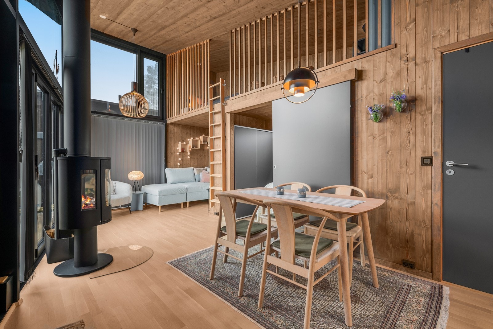 Åpen stue og spisestue med moderne peis og store vinduer som slipper inn naturlig lys. Galleribilde