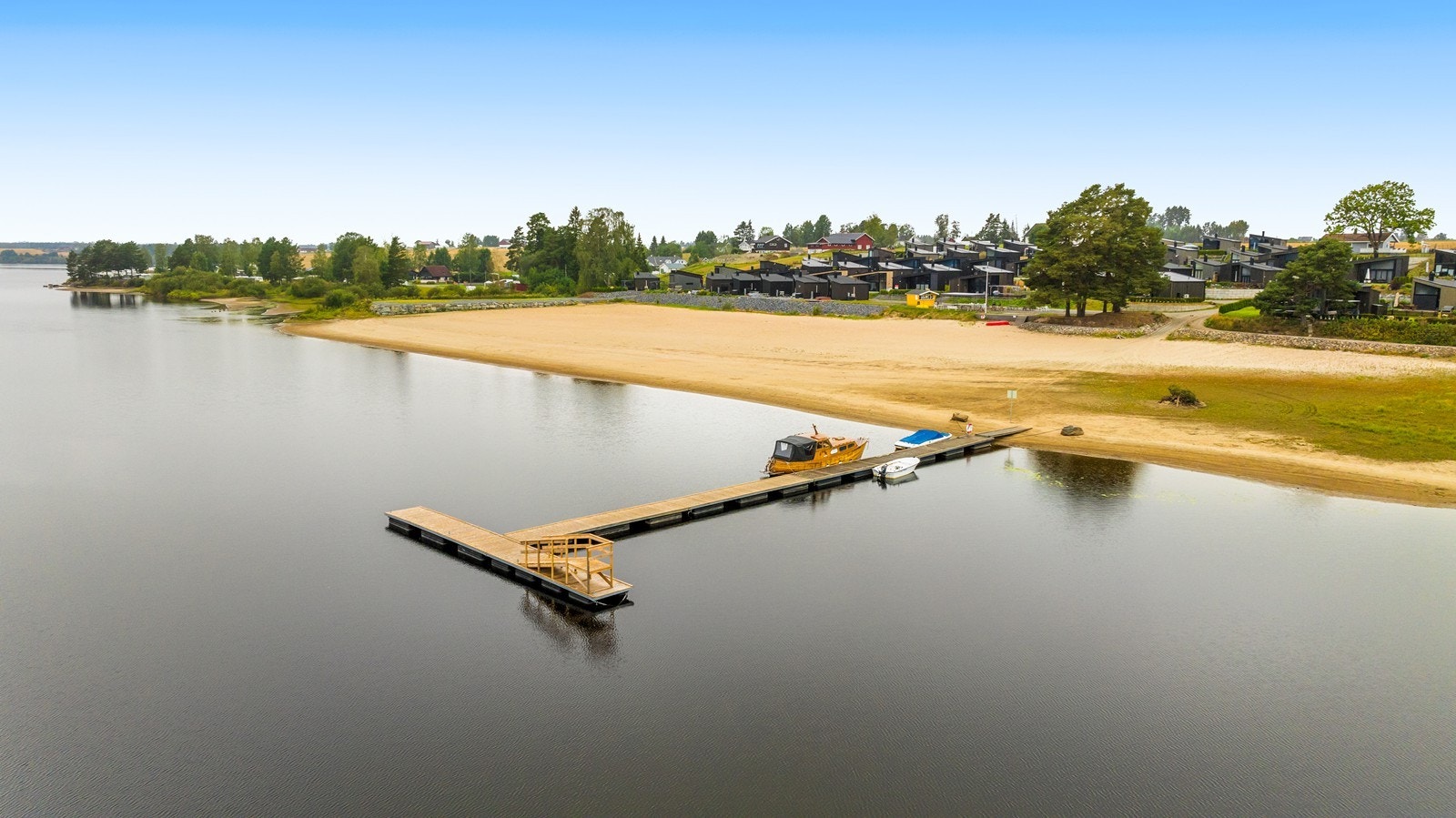 Dronefoto av badebrygge og strand, med muligheter for bading og båtliv. Galleribilde