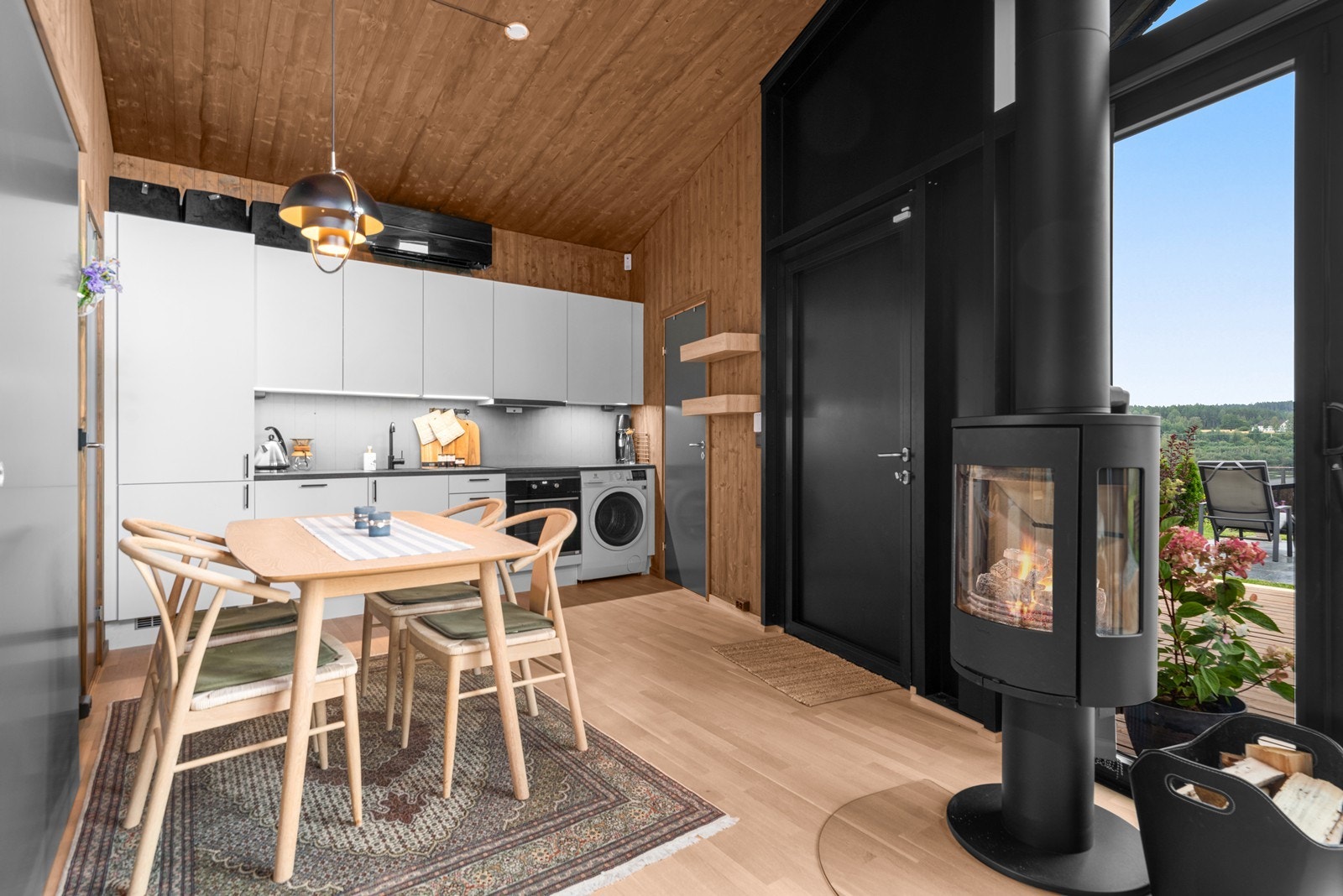 Spiseplass med moderne kjøkkeninnredning og peis som skaper en hyggelig atmosfære. Galleribilde