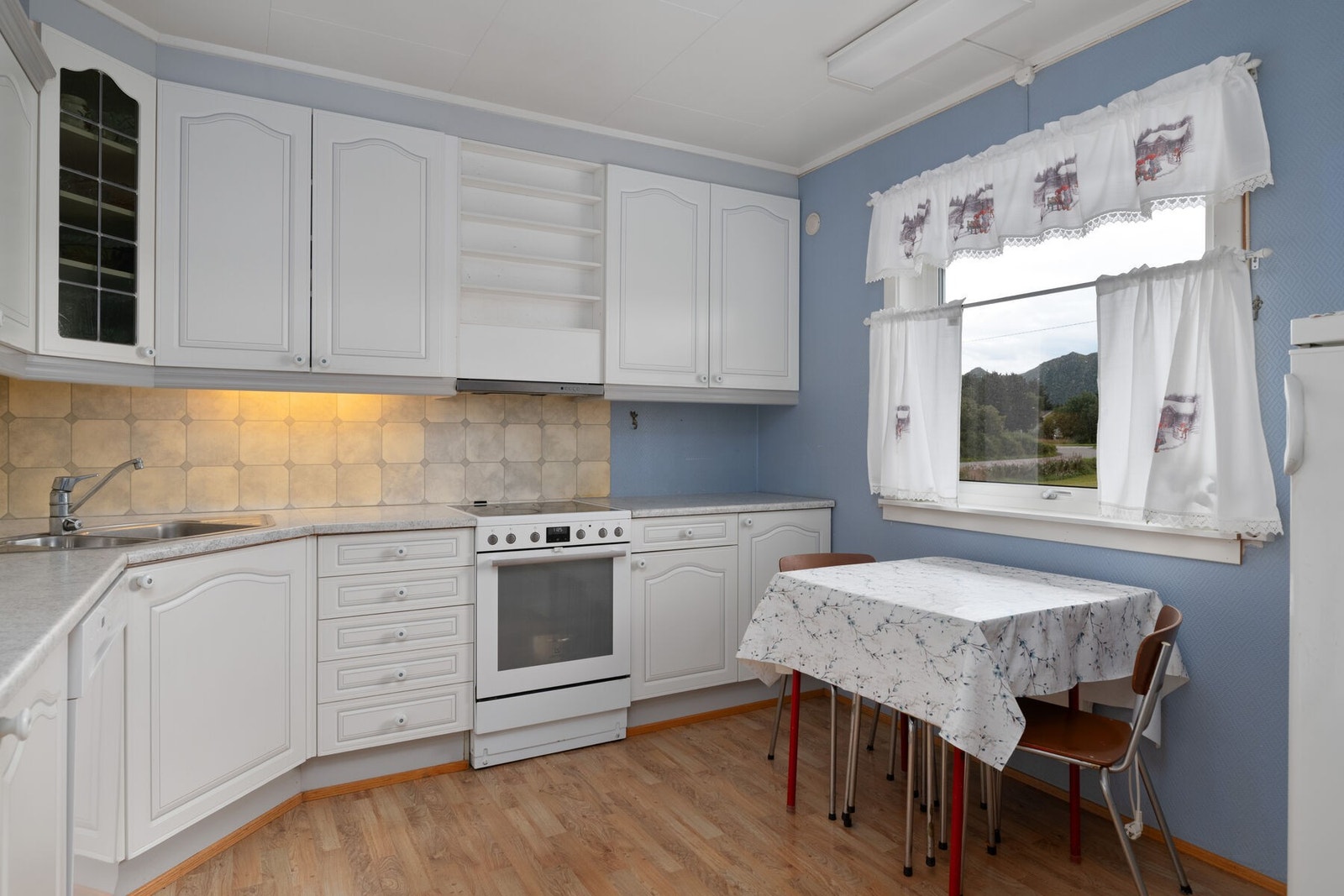 Kjøkkeninnredningen har profilerte fronter, laminat benkeplate og opplegg for frittstående hvitevarer. Galleribilde