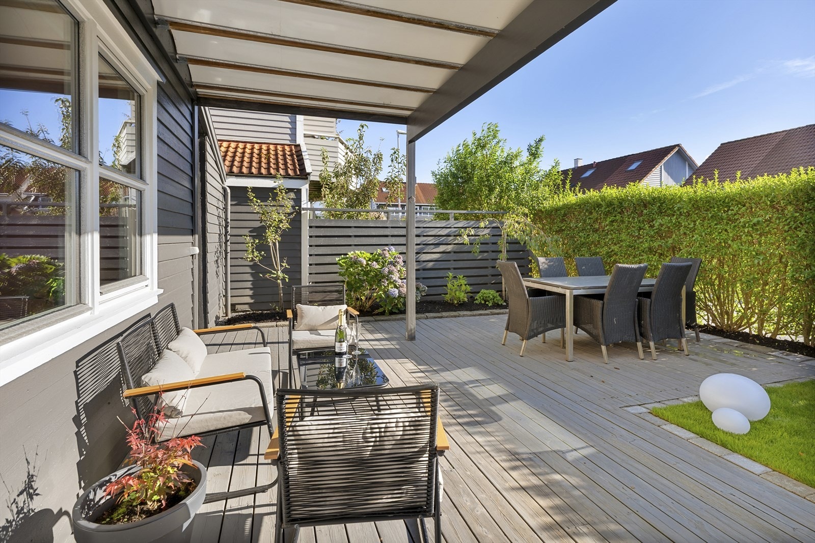 Velstelt hageområde med gressplen og en romslig terrasse med utgang fra underetasjen. Galleribilde