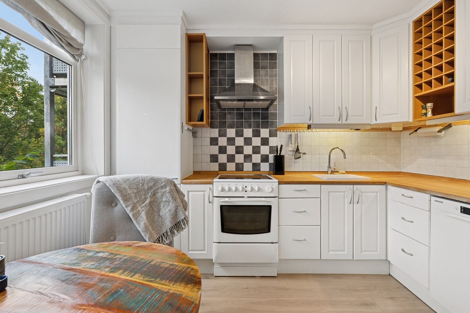 Kjøkkenet har heltre benkeplate og nedfelt vask i hvit porselen Galleribilde