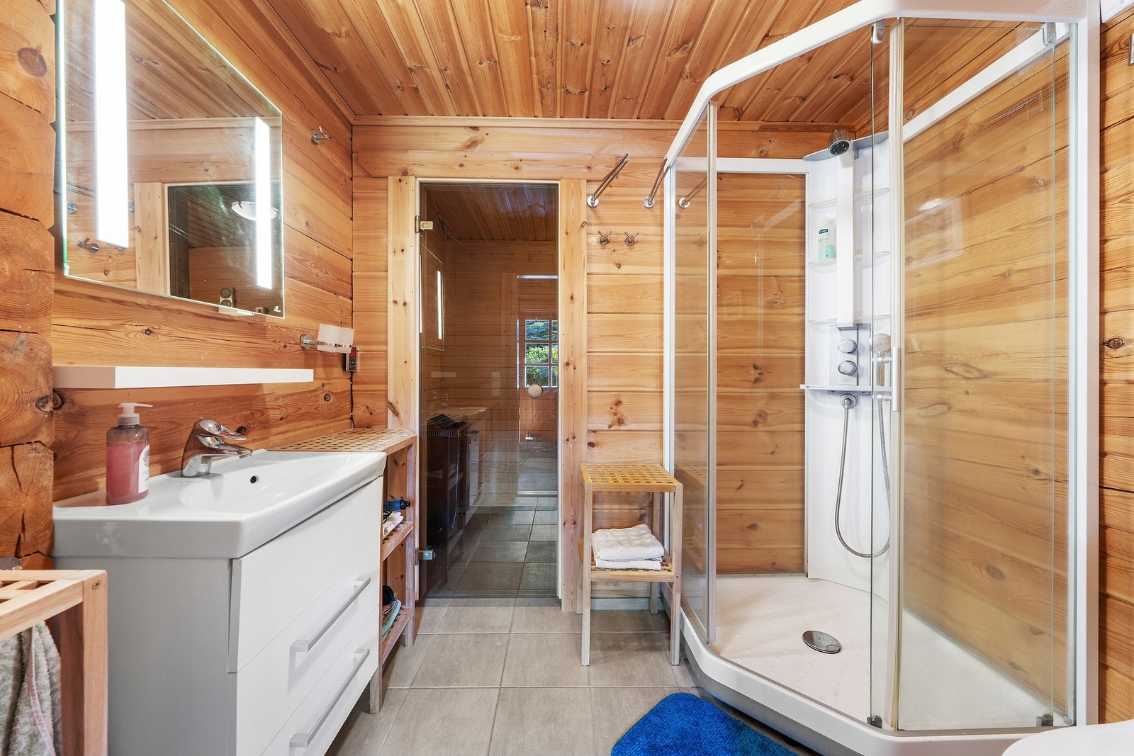 Baderom med dusj og praktiske løsninger. I tillegg finner du en separat bastu som gir en ekstra luksuriøs følelse, perfekt for avslapning etter en lang dag. Galleribilde