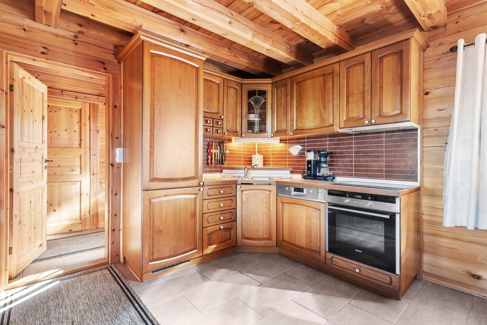 Et lunt og praktisk kjøkken i heltre. Et kjøkken som gir ekte hyttestemning og plass til gode måltider. Galleribilde