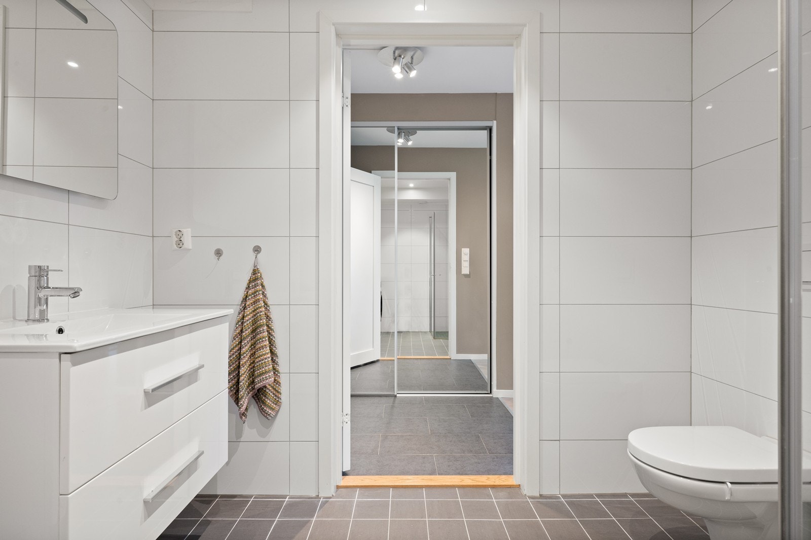 Det er hvit baderomsrinnredning med heldekkende servant med skuffer under. Galleribilde