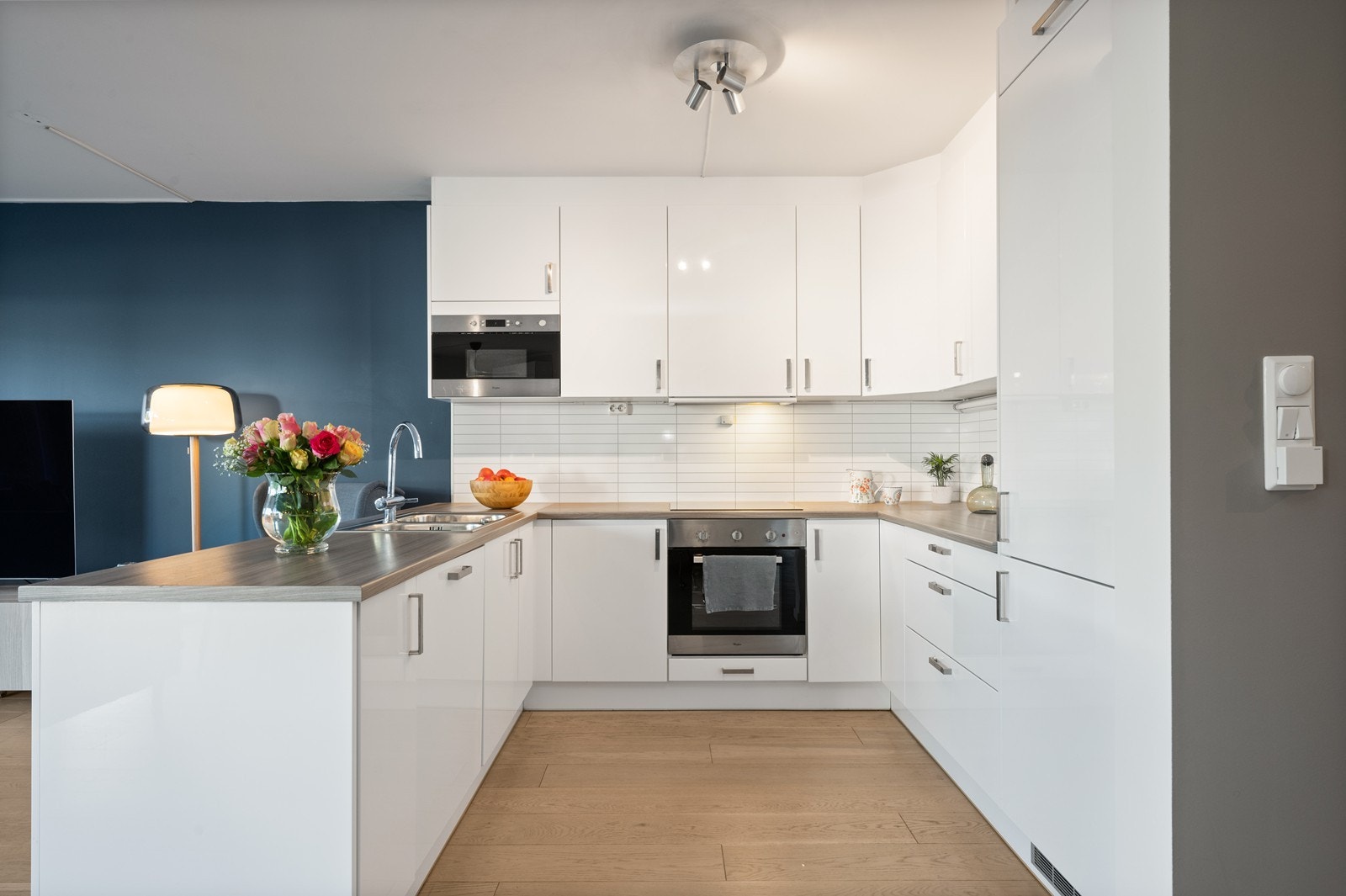 Pent kjøkken i hvit utførelse. Det er glatte fronter og laminat benkeplater. Galleribilde