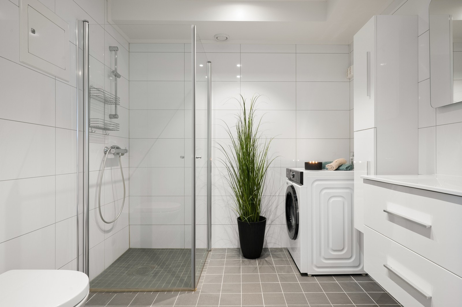 Leiligheten har et delikat bad som er flislagt på gulv og vegger. Fargevalget er tidløst og det er praktisk dusjløsning med glassvegger. Galleribilde