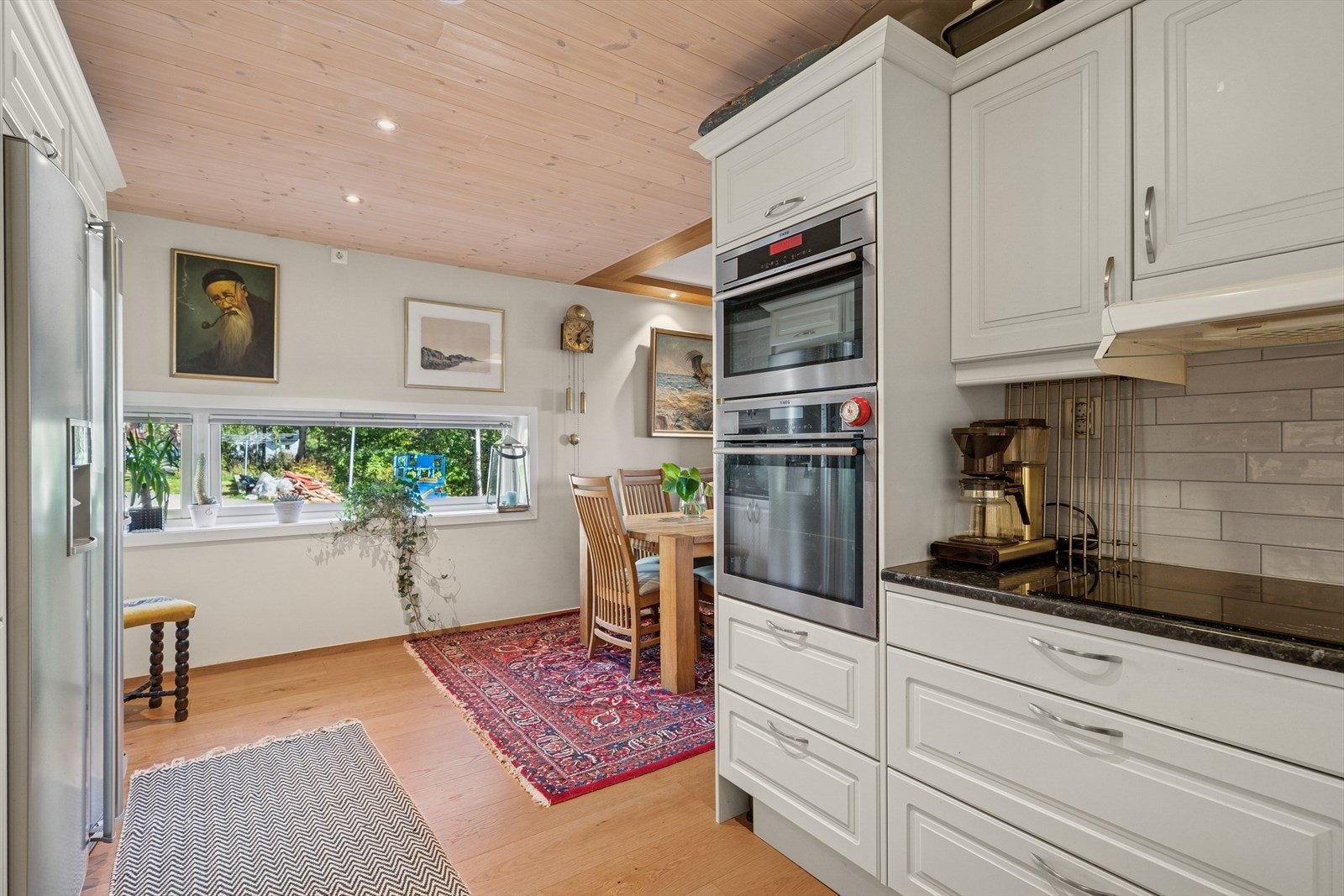 Kjøkkeninnredning med under-/overskap og profilerte fronter, benkeplater av laminat med planlimt kum i rustfritt stål og ett-greps blandebatteri. Galleribilde