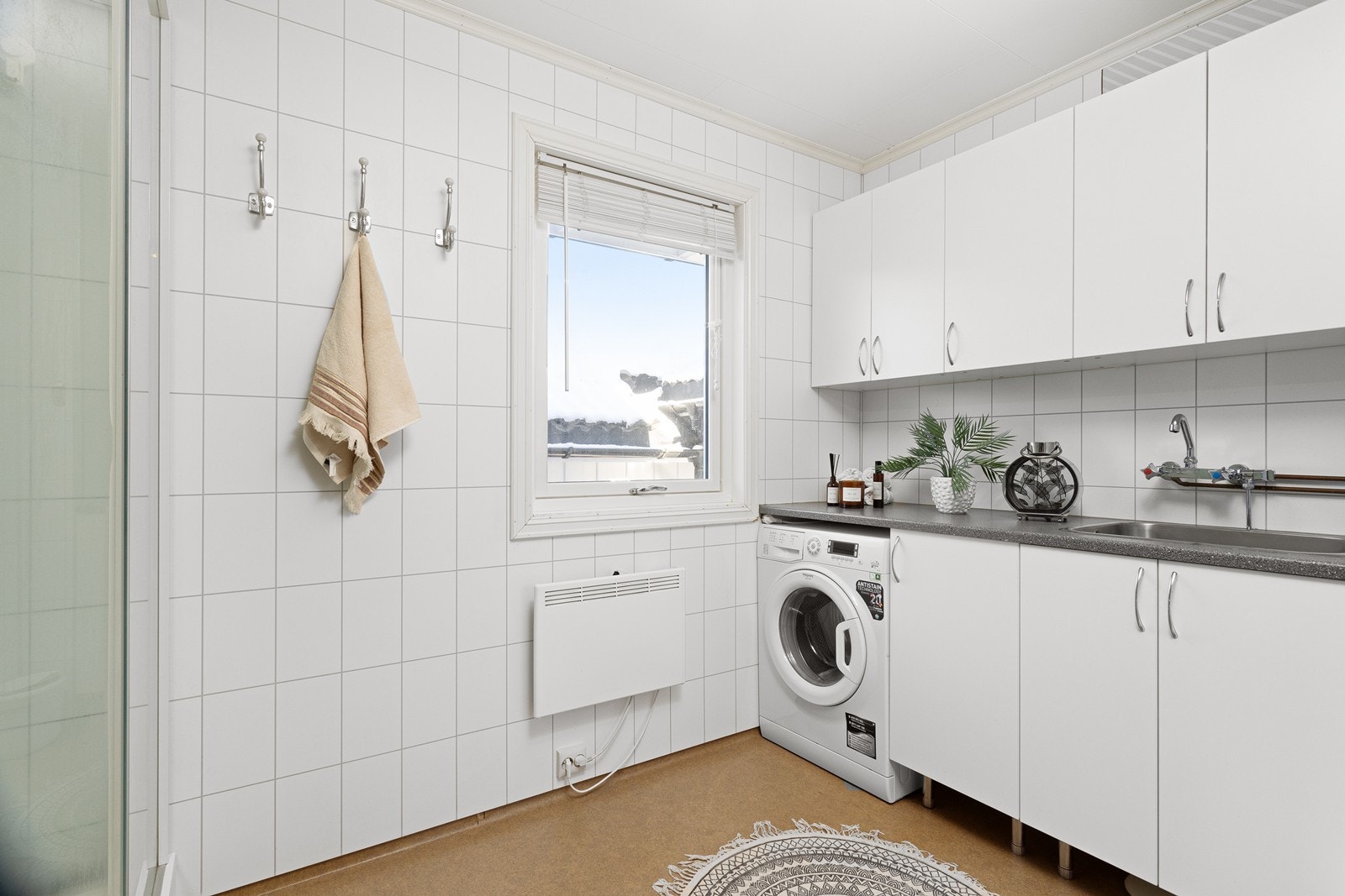 Badet i 1.etasje har belegg på gulv og utstyrt med nedfelt utslagsvask, dusjkabinett og opplegg for vaskemaskin i en praktisk innredning med mye skapplass. Galleribilde