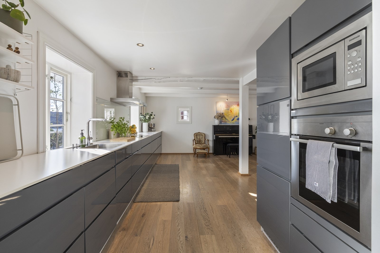 Kjøkken fra Kvikk er utstyrt med grå høyglans kjøkkeninnredning fra 2010, kompakt laminat benkeplate og integrerte hvitevarer Galleribilde