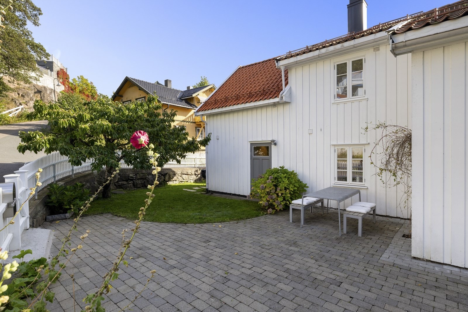 Vakker hage inngjerdet med Drøbak stakitt gjerde og opparbeidet med belegningsstein, gressplen, frukttrær og bed Galleribilde