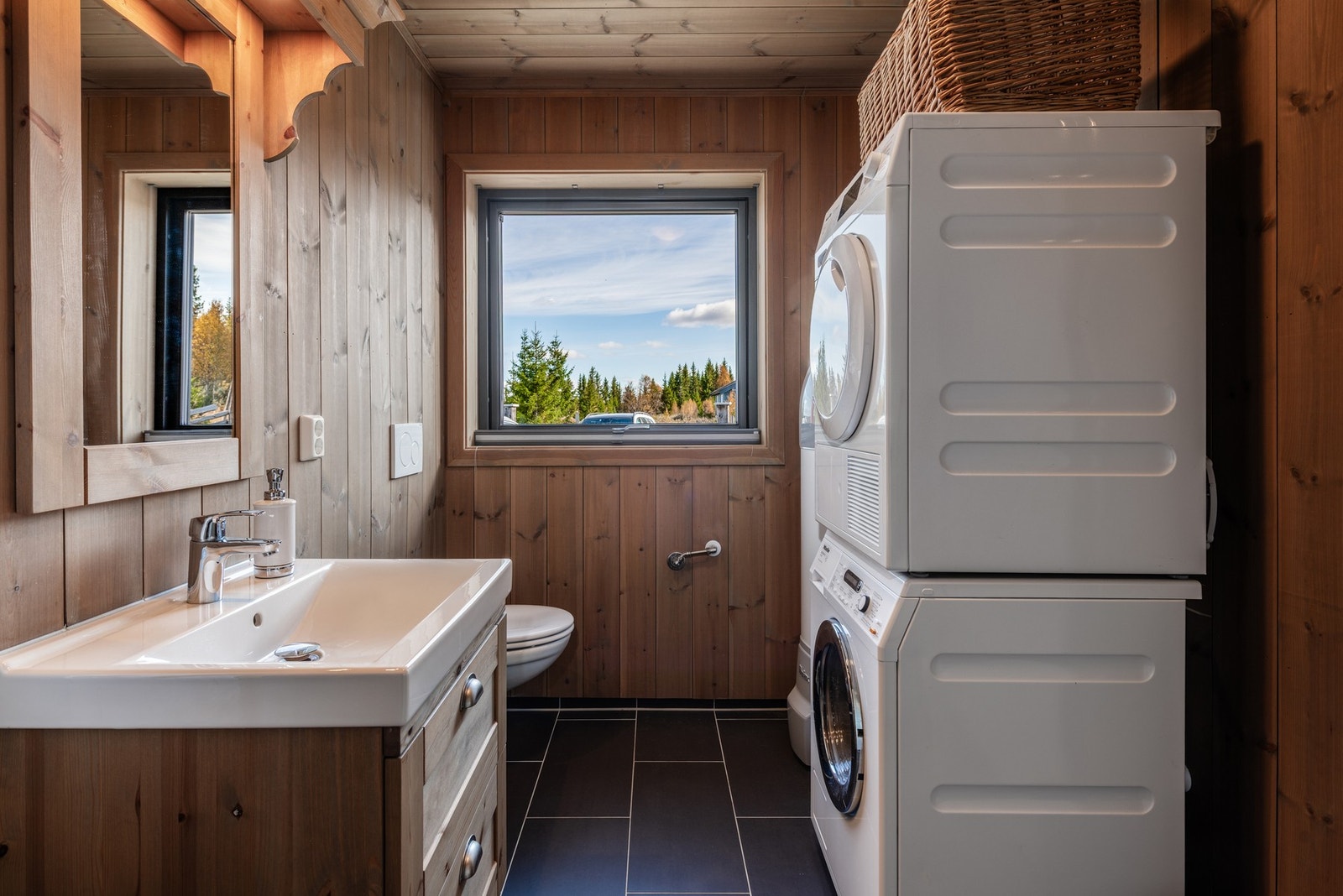 Bad/Vaskerom er innredet med dusj, toalett, servant med innredning, opplegg for vaskemaskin og tørketrommel. Galleribilde