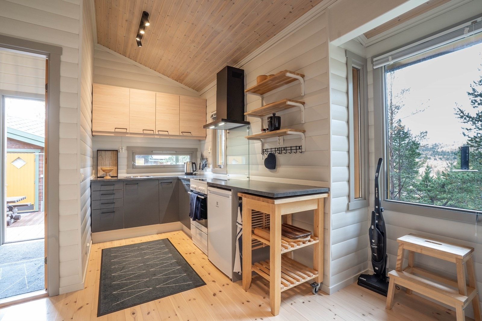 Lys og moderne kjøkkenkrok med store vinduer, praktisk oppbevaring og stilren design. Ideell for matlaging med naturskjønn utsikt. Galleribilde