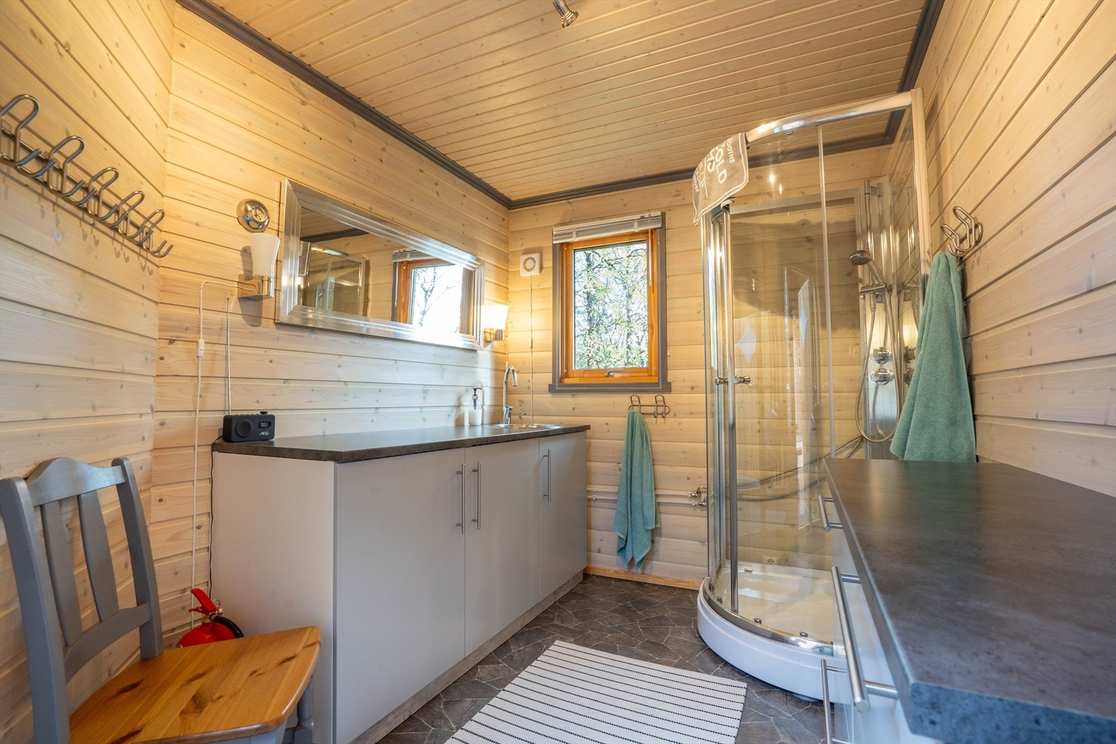 Bad med benk, servant og dusjkabinett. Gråvann ut under bygget. Galleribilde