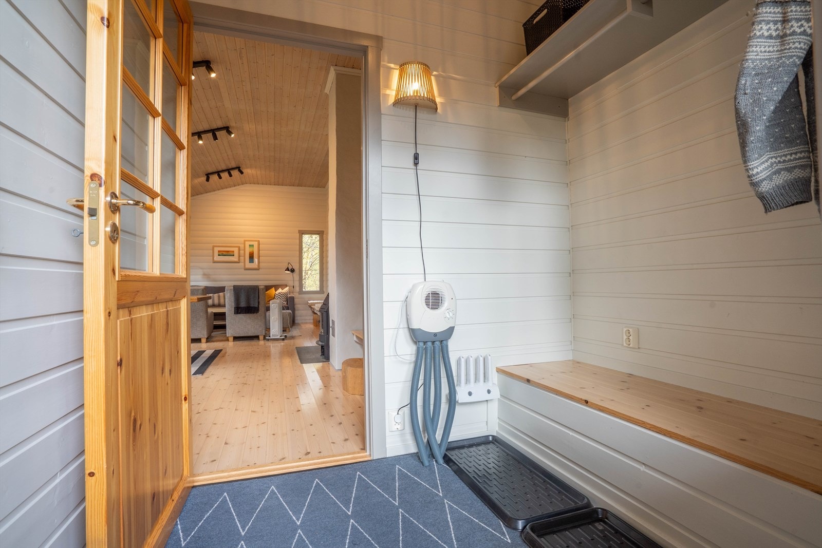 Lys og innbydende entré med praktisk benk og oppheng. Åpen løsning mot stue skaper en varm atmosfære. Perfekt for familiehygge. Galleribilde