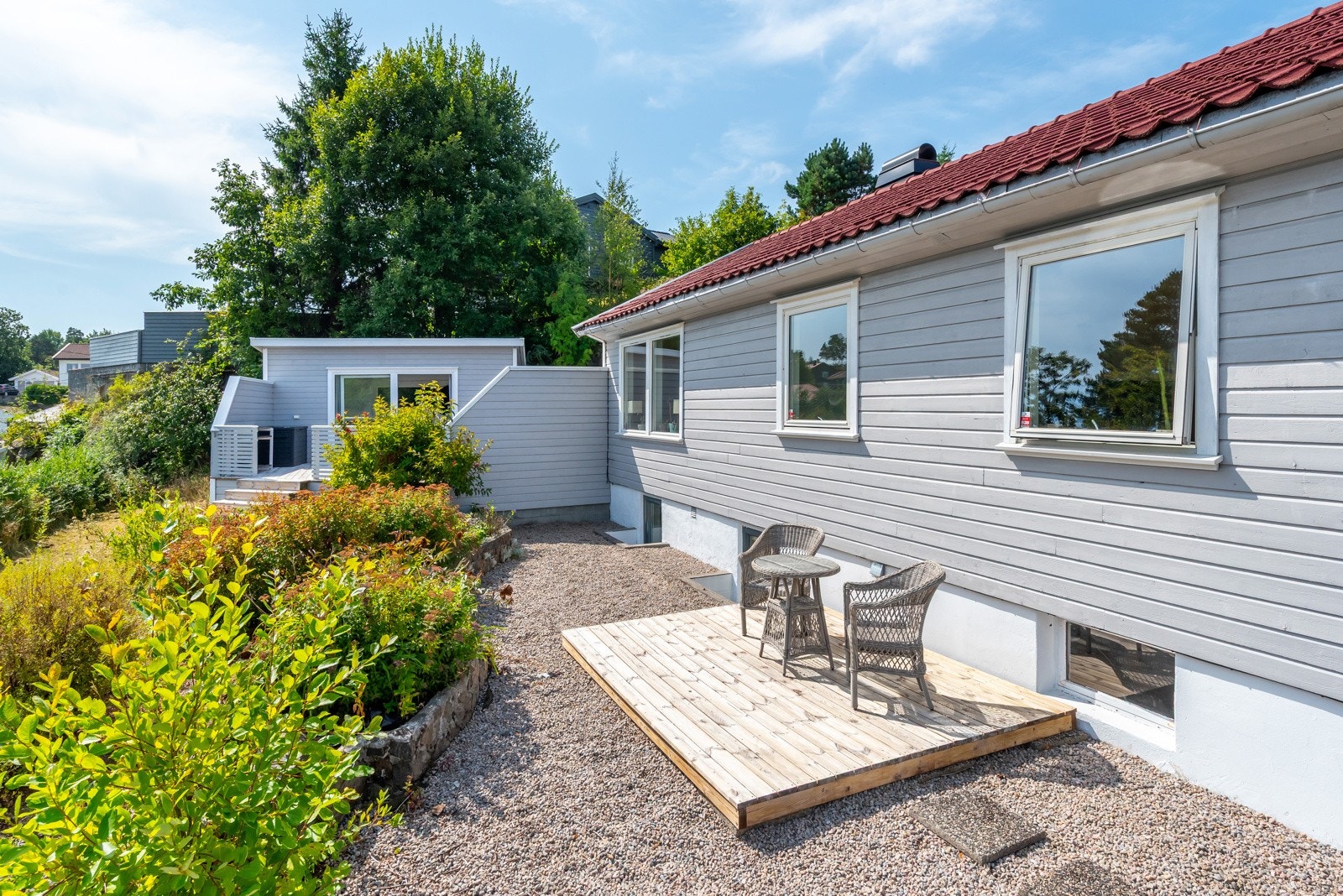 Pent oppgrusset område med prydbusker i bed og platting på fremsiden av boligen. Galleribilde