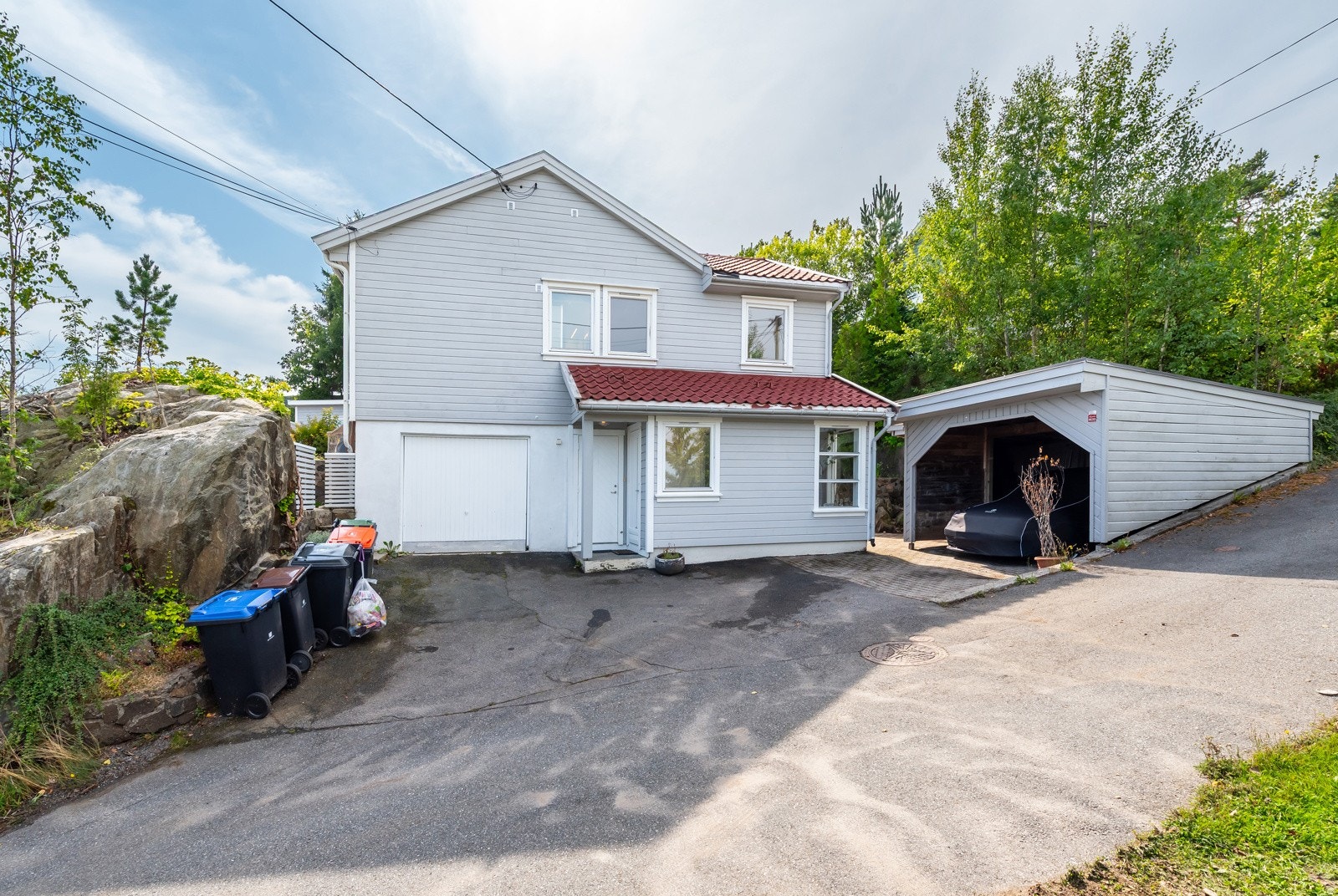 Boligen har integrert garasje og carport. Det er plass til flere biloppstillinger i den asfalterte innkjørselen. Galleribilde