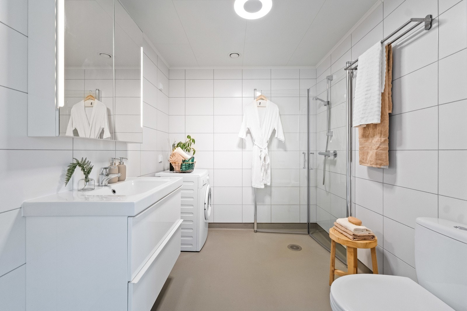 Baderom er fra byggeåret, og fremstår moderne med gulvvarme og tidløs innredning. Badet er utstyrt med servant på benkeskap, speilskap, belysning, gulvstående toalett og dusj med innfellbare dører i herdet glass. Opplegg for vaskemaskin. Galleribilde