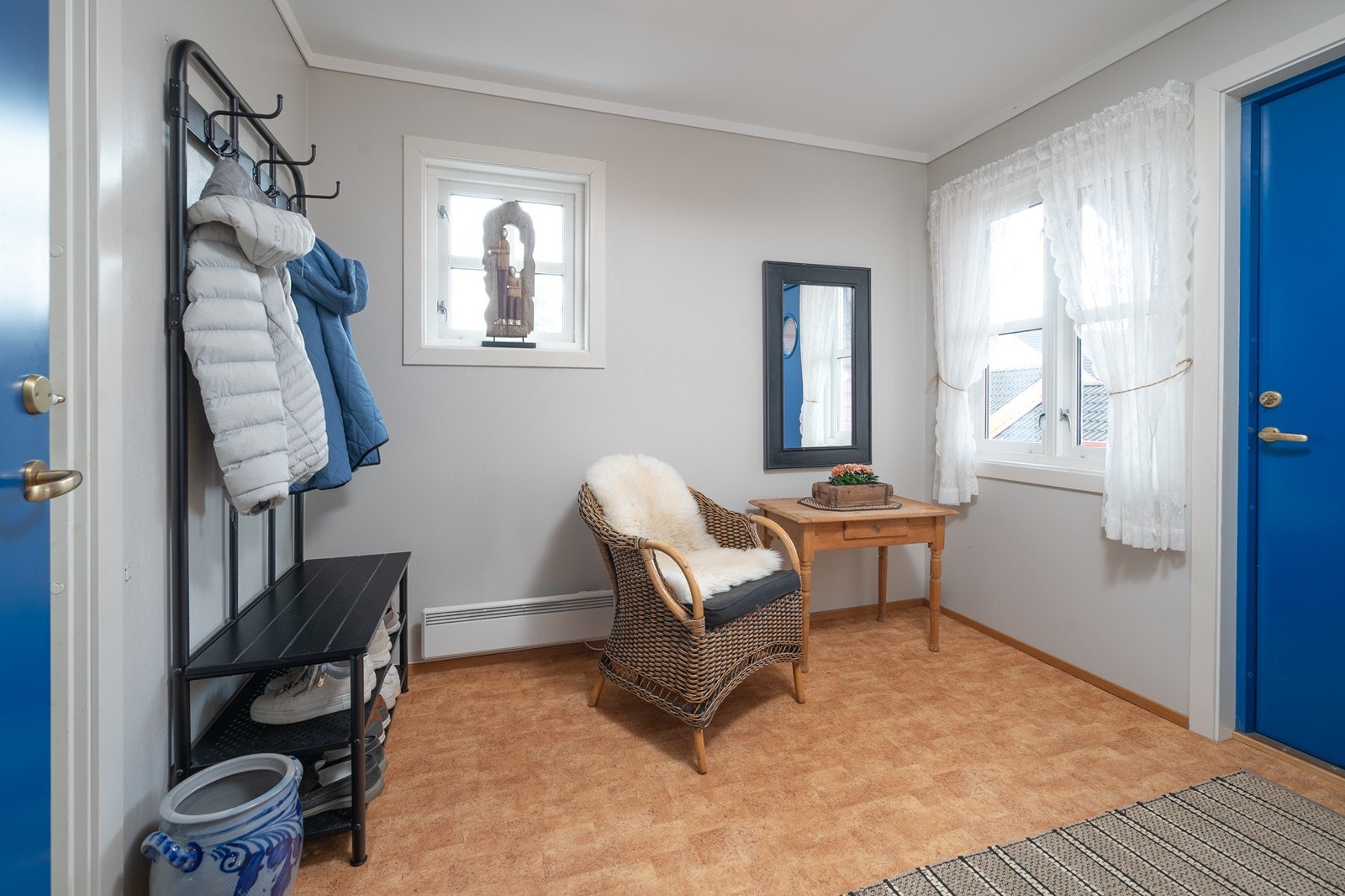 Romslig entré med gråmalte vegger, gulvbelegg og utgang via bod til terrasse i bakhage Galleribilde