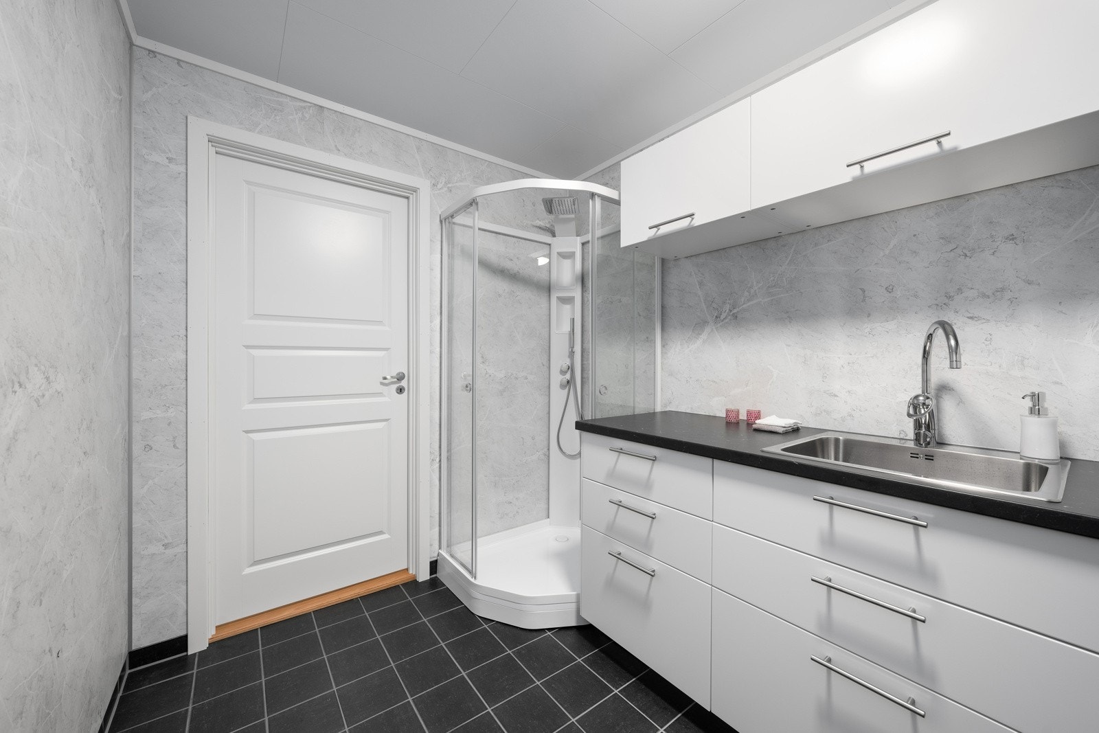 Vaskerommet har steinmønstrede våtromsplater på veggene og grå gulvfliser med gulvvarme Galleribilde