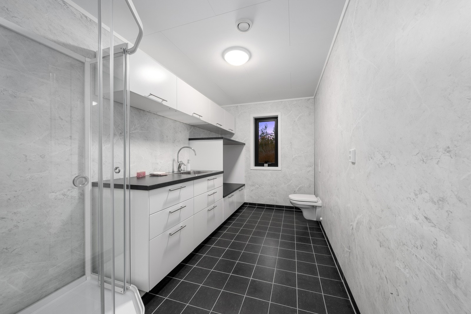 Vaskerom med dusjkabinett, samt avsatt plass til vaskemaskin og tørketrommel i en nisje Galleribilde