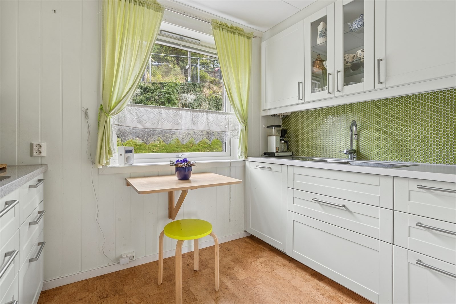 Kjøkken med profilerte hvite fronter og benkeplate i kvarts. Fliser mellom benkeplate og overskap. Integrert stekeovn, mikrobølgeovn, induksjonstopp og oppvaskmaskin. Galleribilde