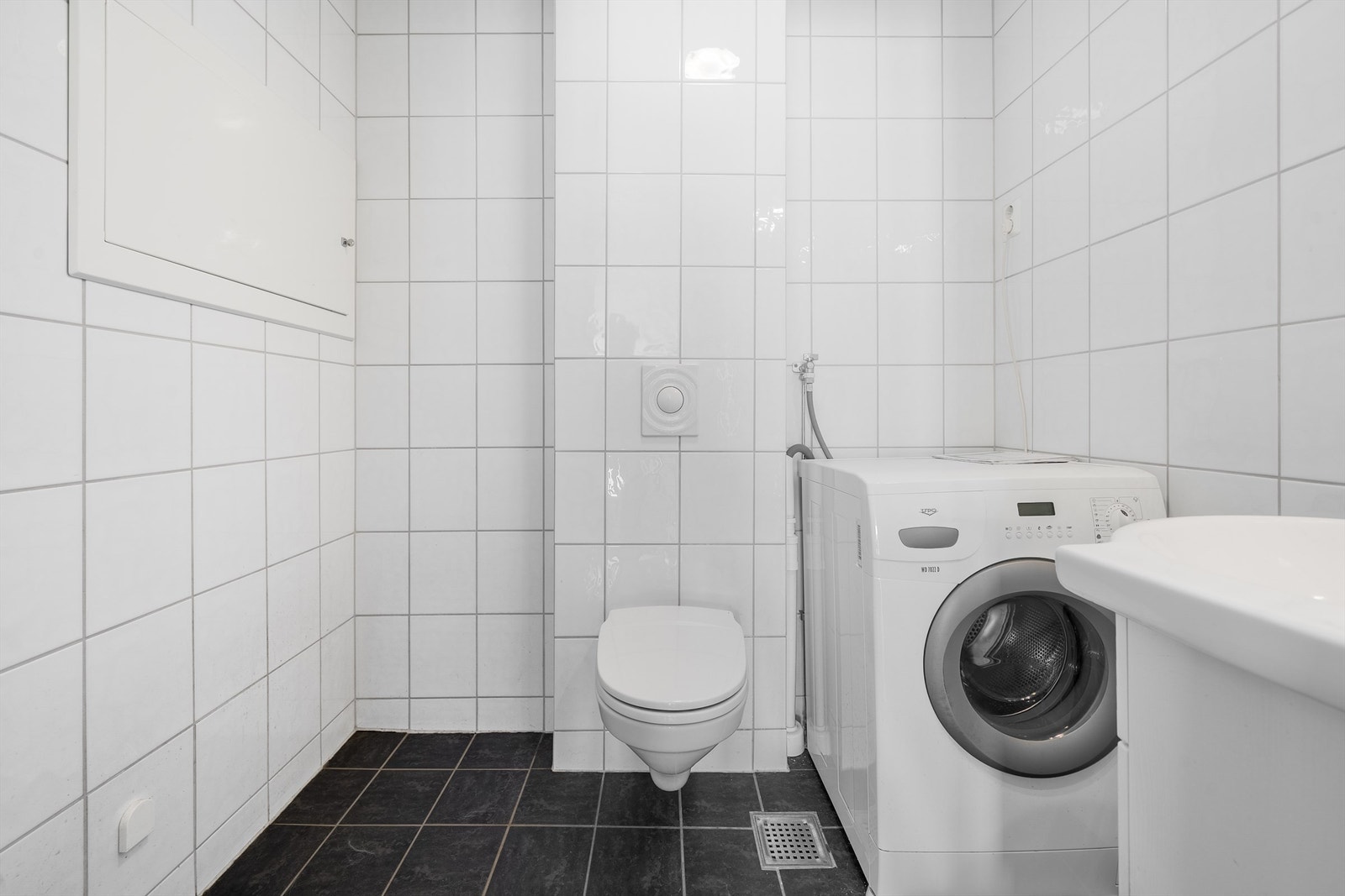 Lys flislagt bad med opplegg for vaskemaskin Galleribilde