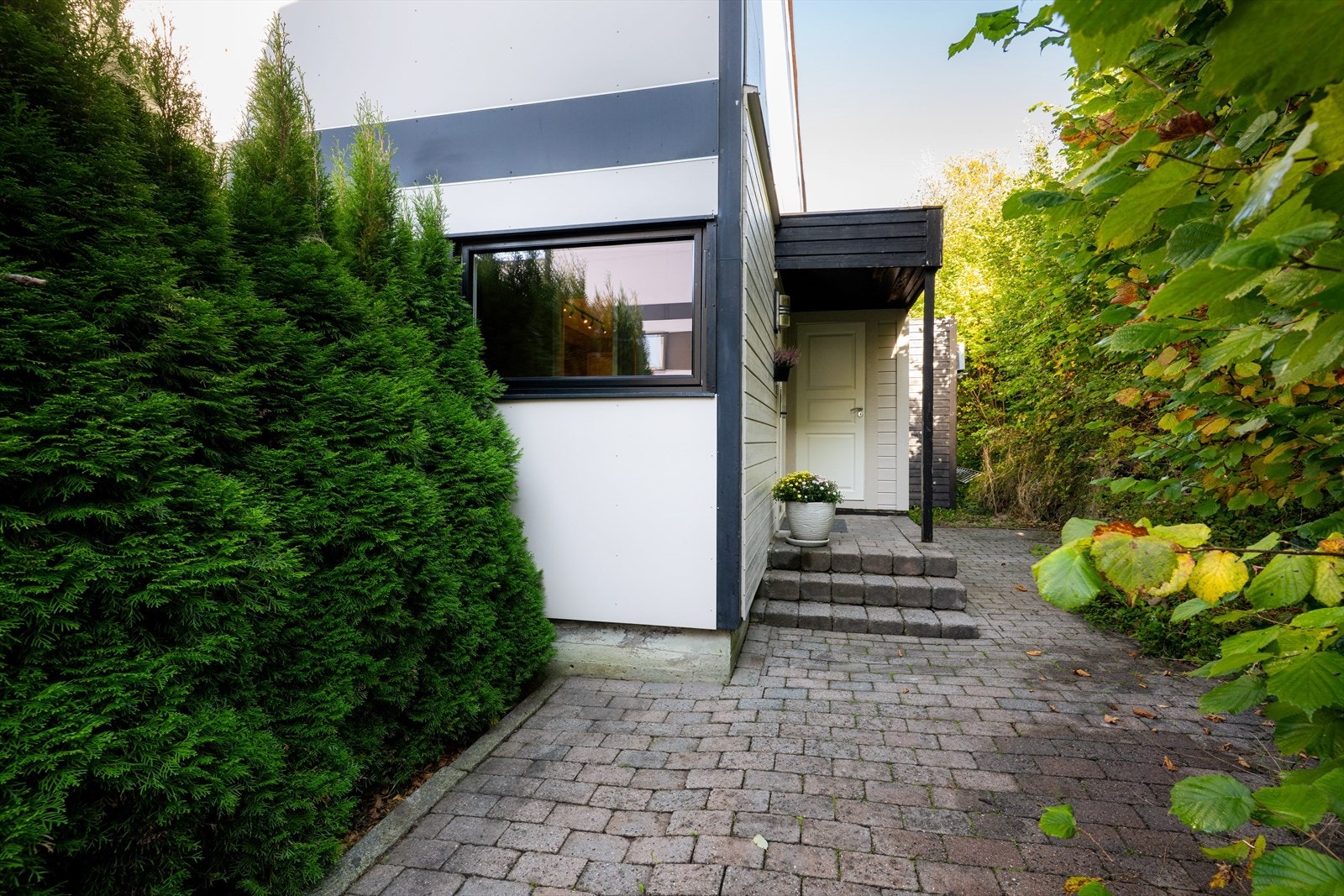 Inngangspartiet ligger usjenert til mot øst, med belegningsstein. Ved inngangspartiet er det etablert en hyggelig og usjenert uteplass. Galleribilde