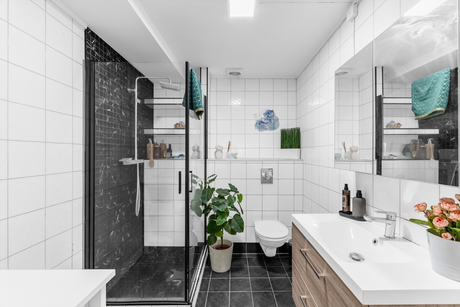 Dusjhjørne med inn-/utadslående dør i herdet glass og vegghengt toalett. Galleribilde