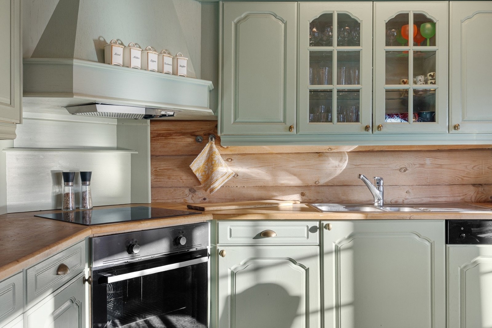 Pent kjøkken med malte profilerte fronter og heltre benkeplate. Integrerte hvitevarer som stekeovn, platetopp, oppvaskmaskin og kjøleskap. Galleribilde