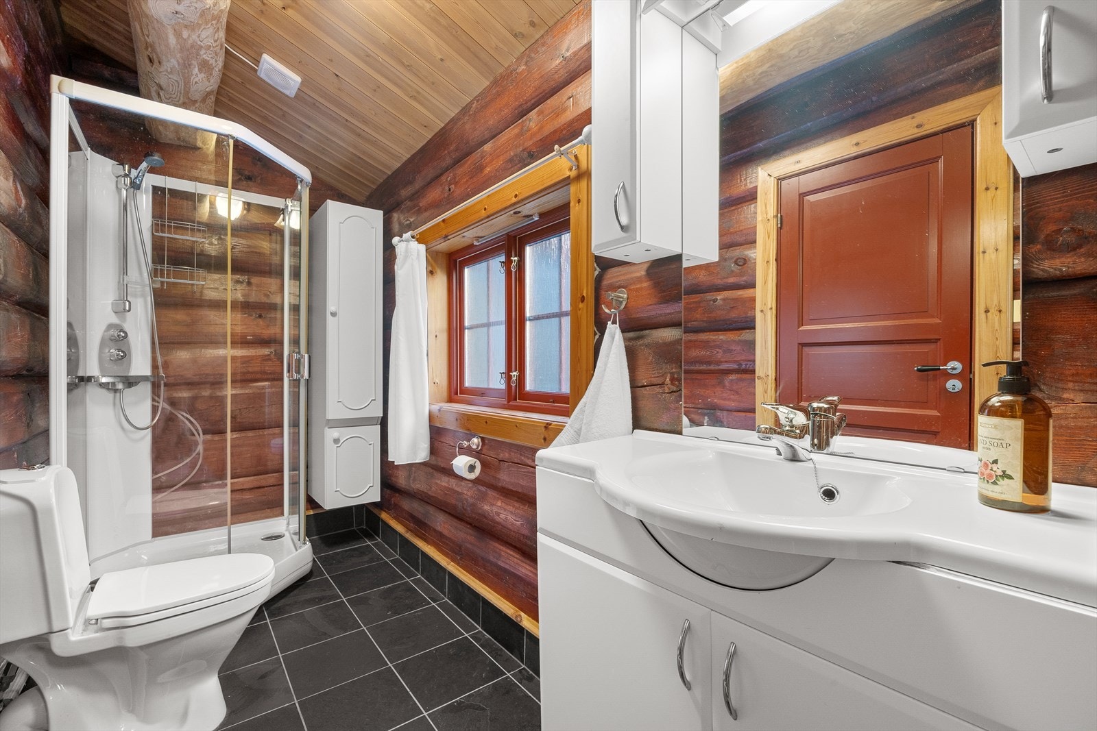 Baderom innredet med toalett, dusjkabinett, servant og baderomsinnredning. Galleribilde